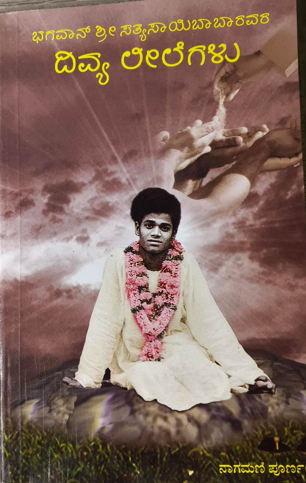 Paperback book titled Bhagawan Sri Sathya Sai Baba Vara Divya Lilegalu with image of young Sai Baba wearing flower garlands