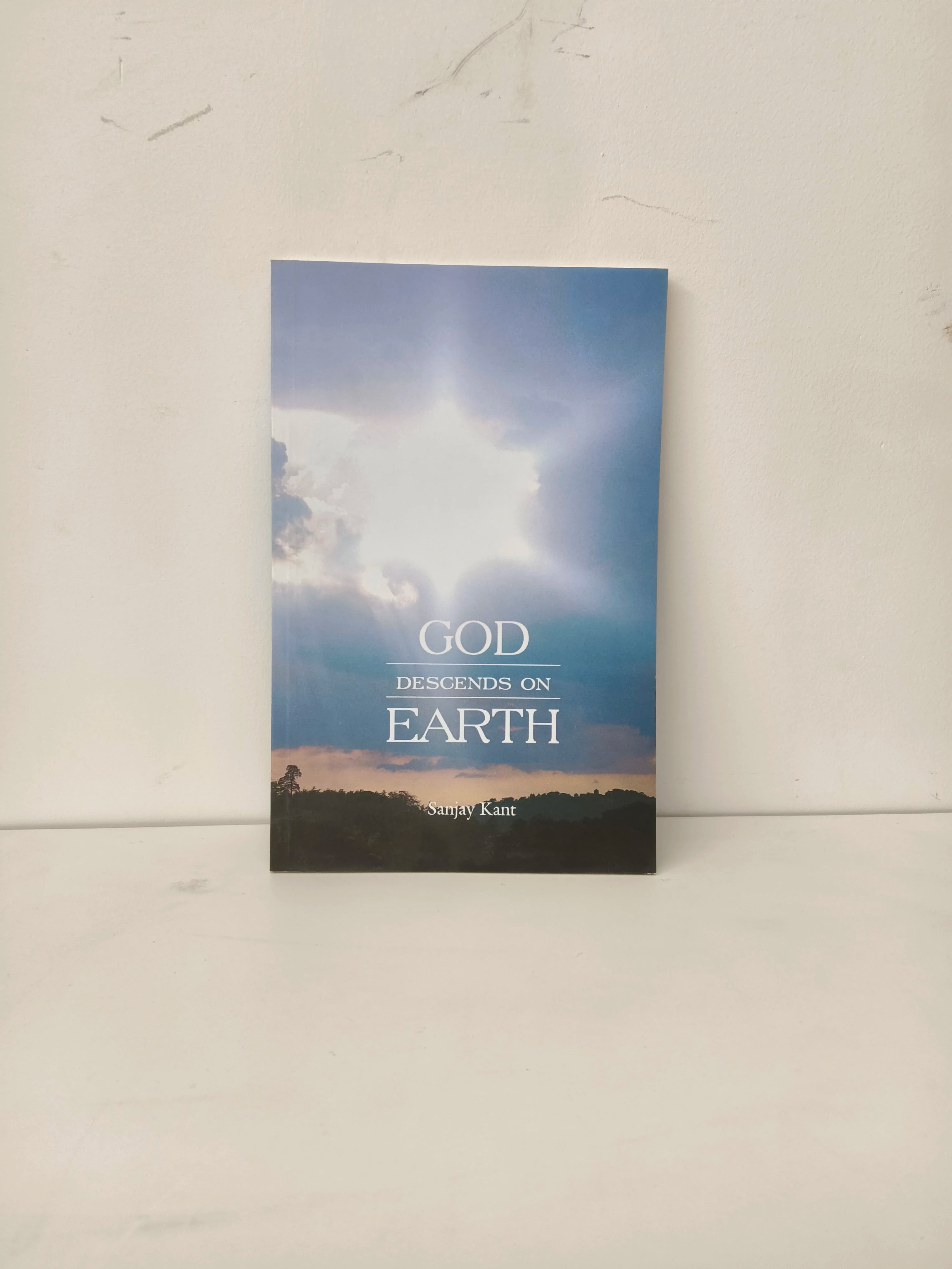 Paperback book titled God Descends On Earth by Sanjay Kant with sky and light cover