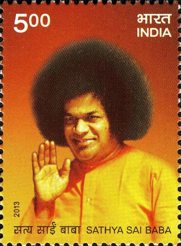 Commemorative stamp featuring Sathya Sai Baba with raised hand on orange background