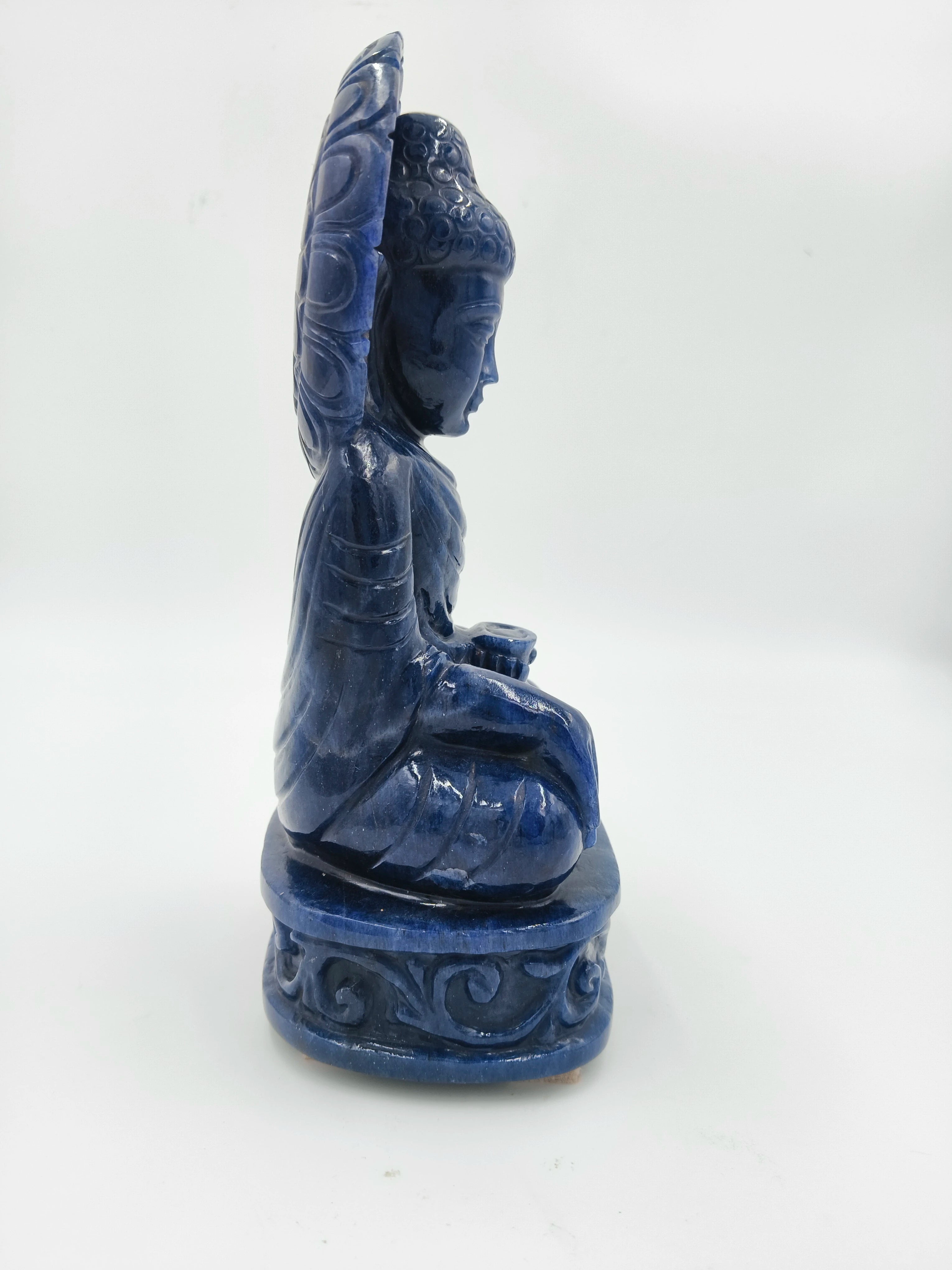 Side view of a blue jade Buddha sculpture seated on a decorative base