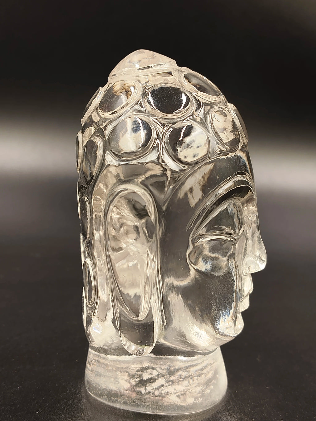 Side view of a clear crystal Buddha head sculpture with detailed features
