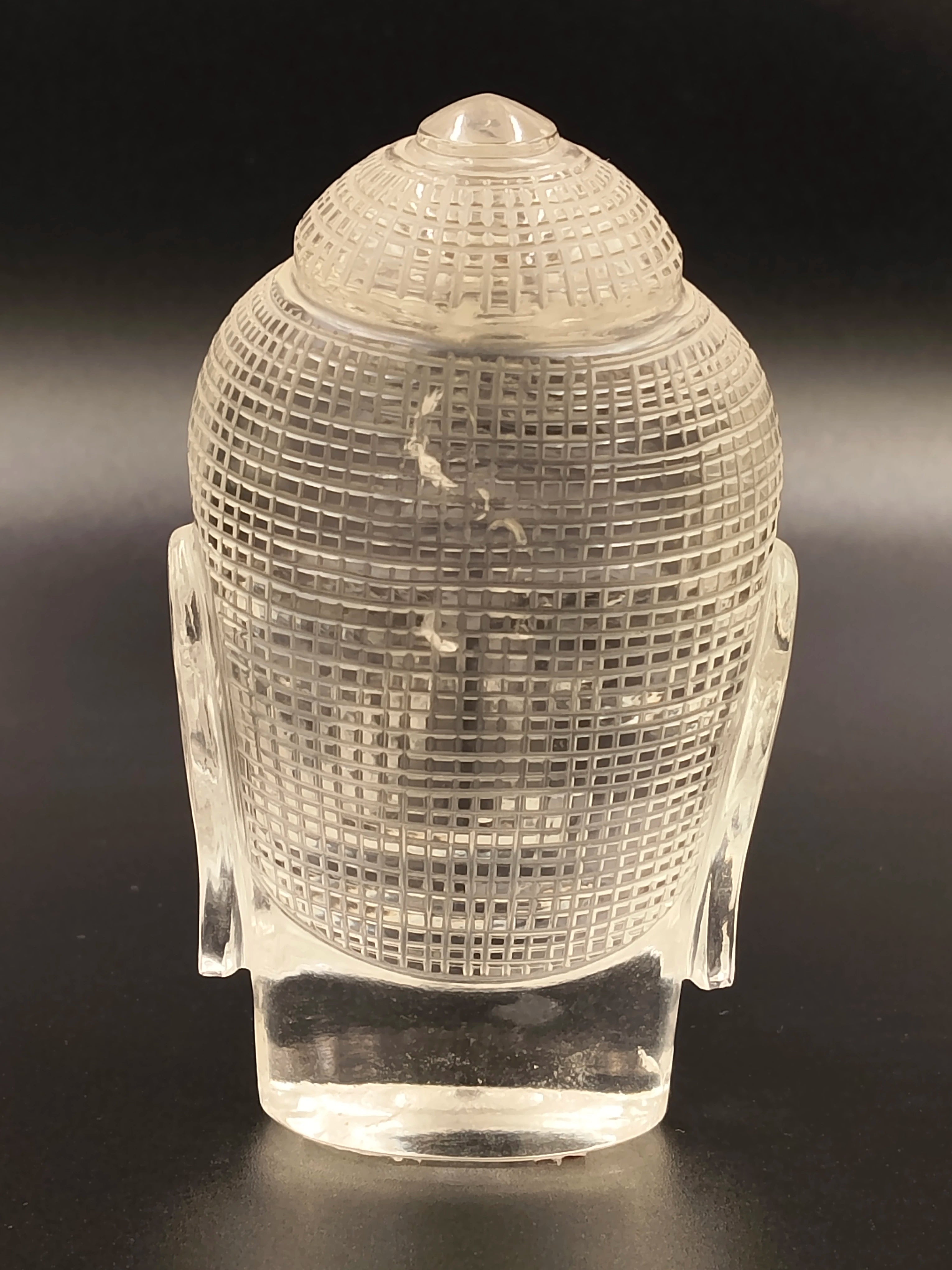 Rear view of a clear crystal Buddha head sculpture with textured surface