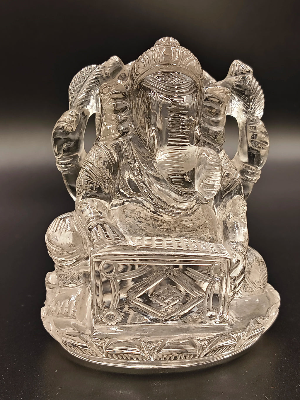 Clear crystal sculpture of Hindu deity Ganesh playing a musical instrument