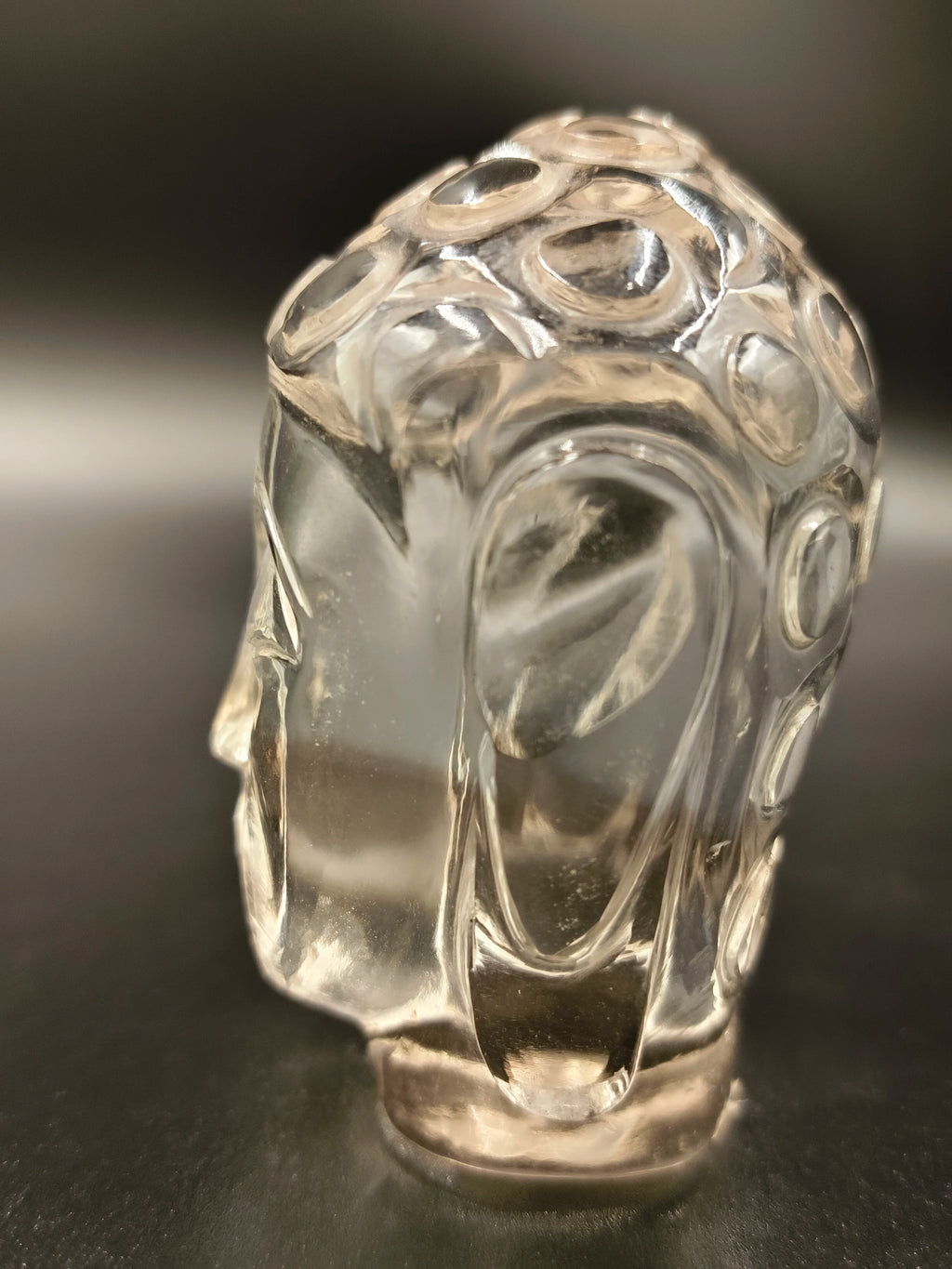 Clear crystal Buddha head sculpture with carved circular patterns