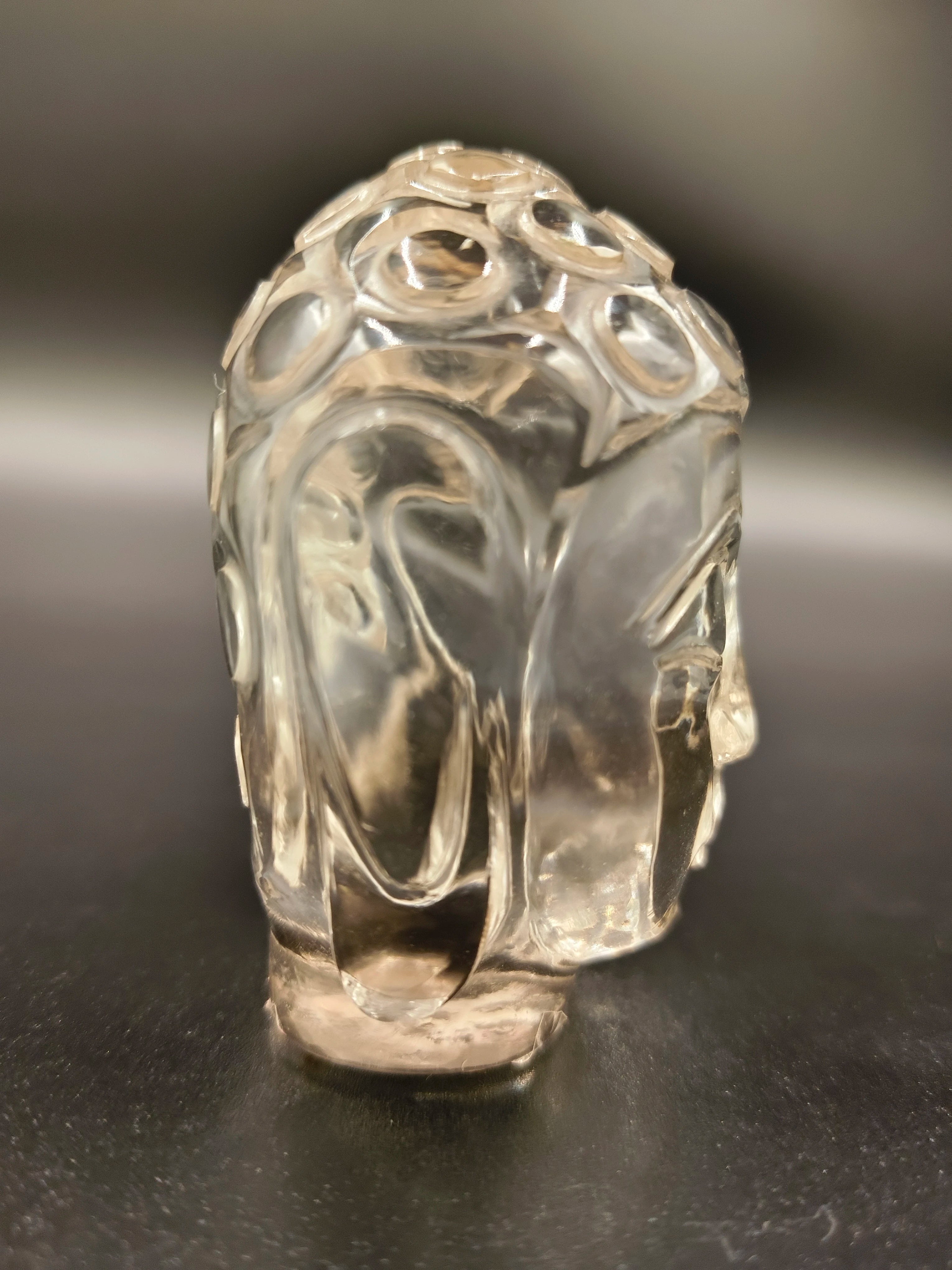 Clear crystal Buddha head sculpture with intricate carvings, front view