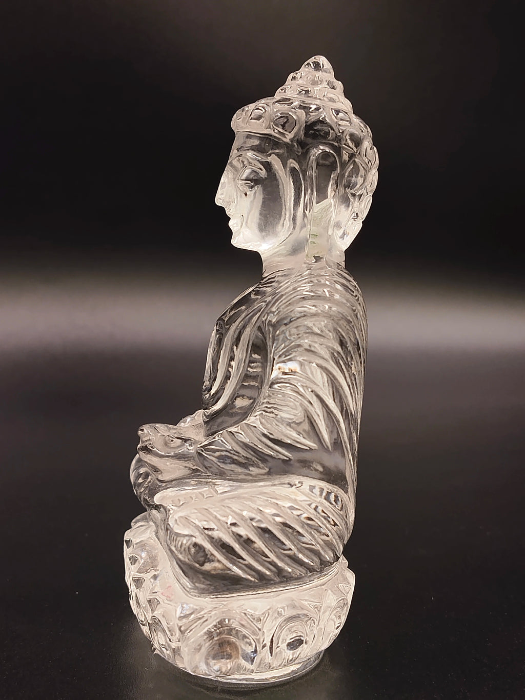 Clear crystal Buddha statue in meditation pose, side view