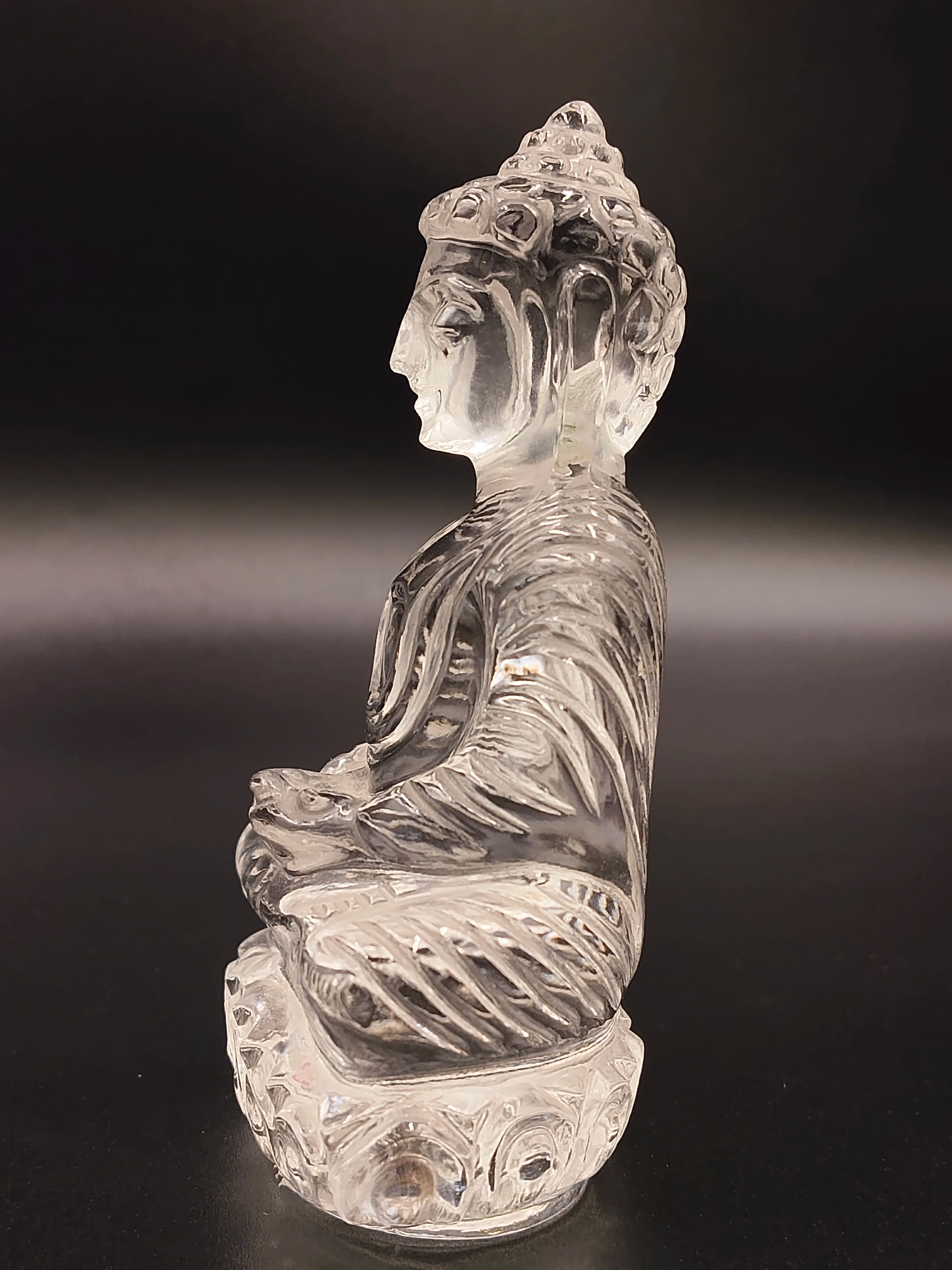 Clear crystal Buddha statue in meditation pose, side view