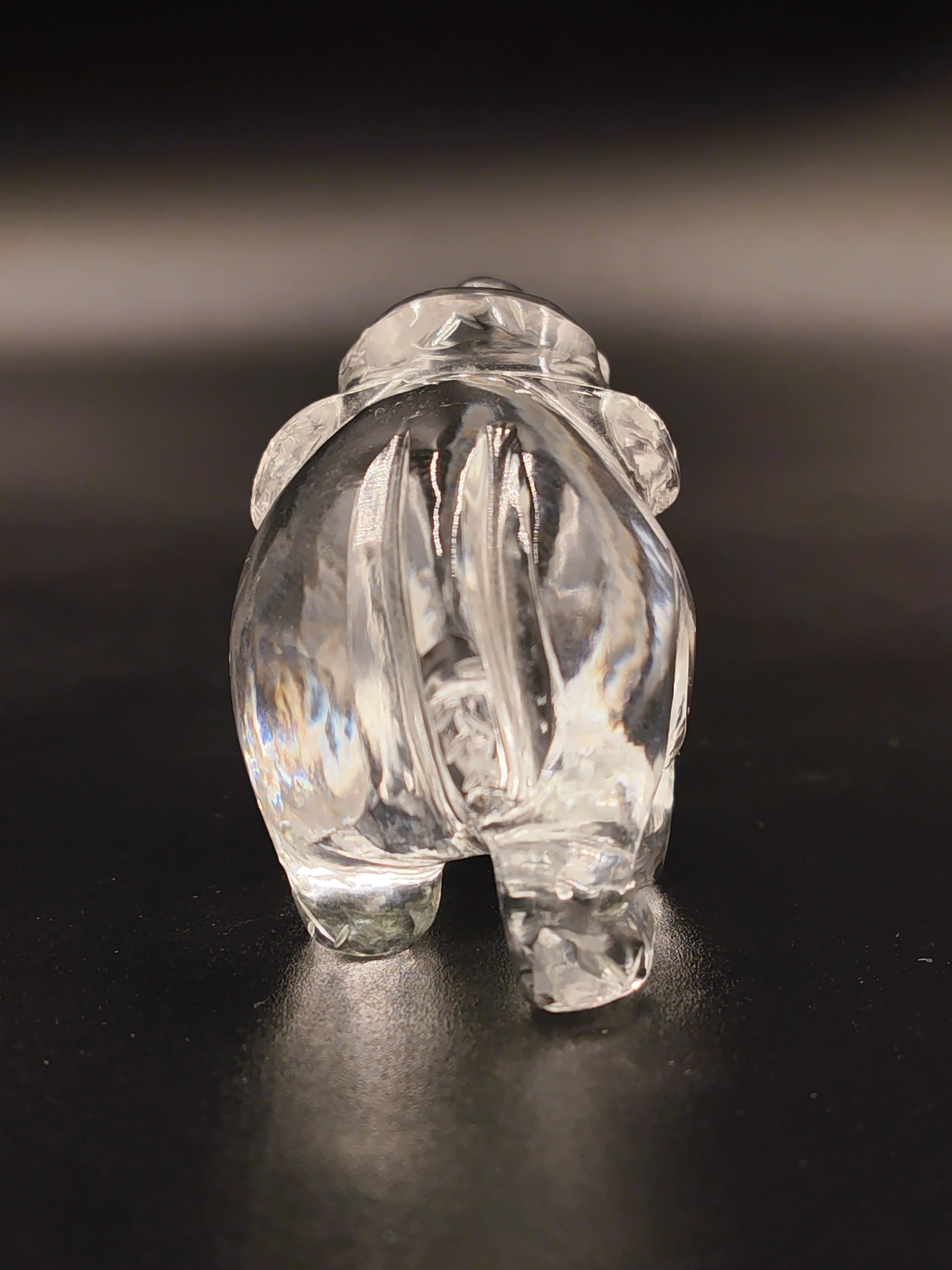 Back view of a clear crystal elephant figurine on dark surface