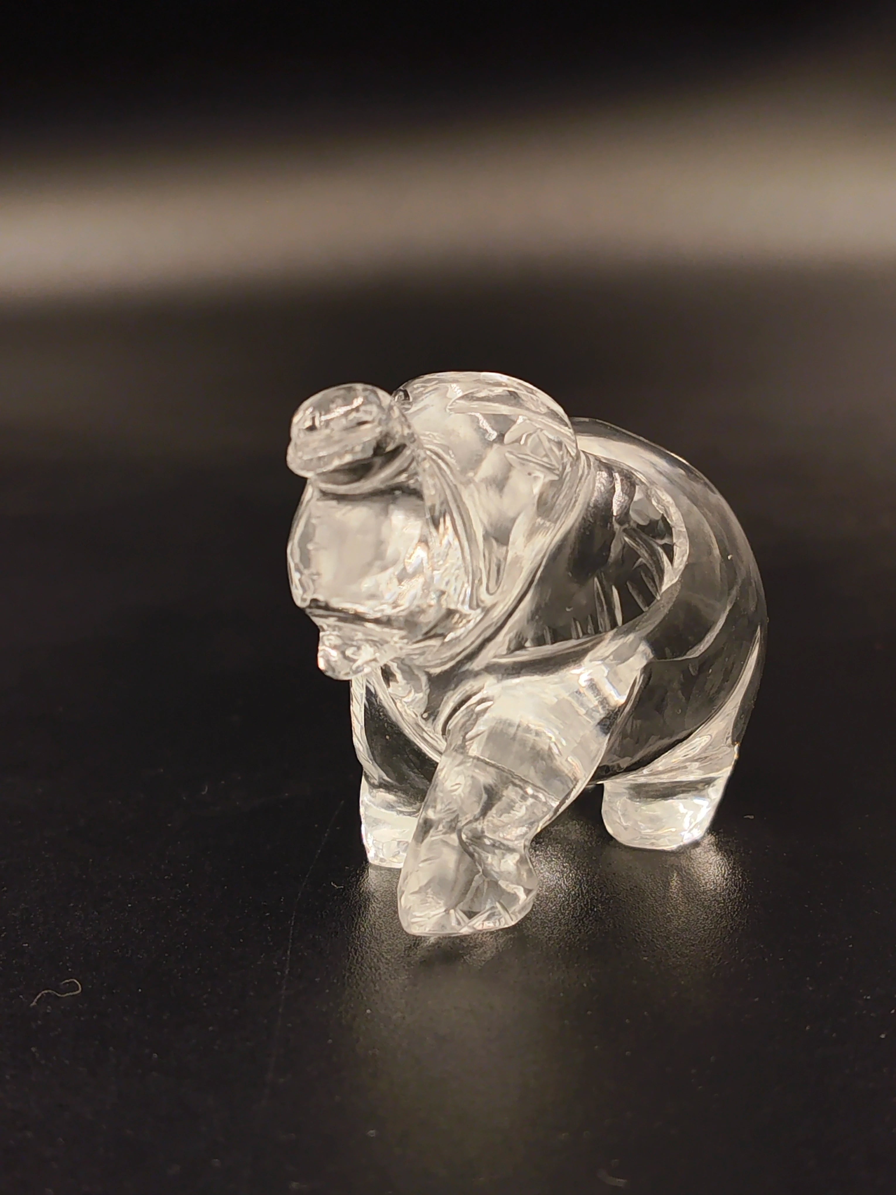 Miniature clear crystal elephant figurine on black surface