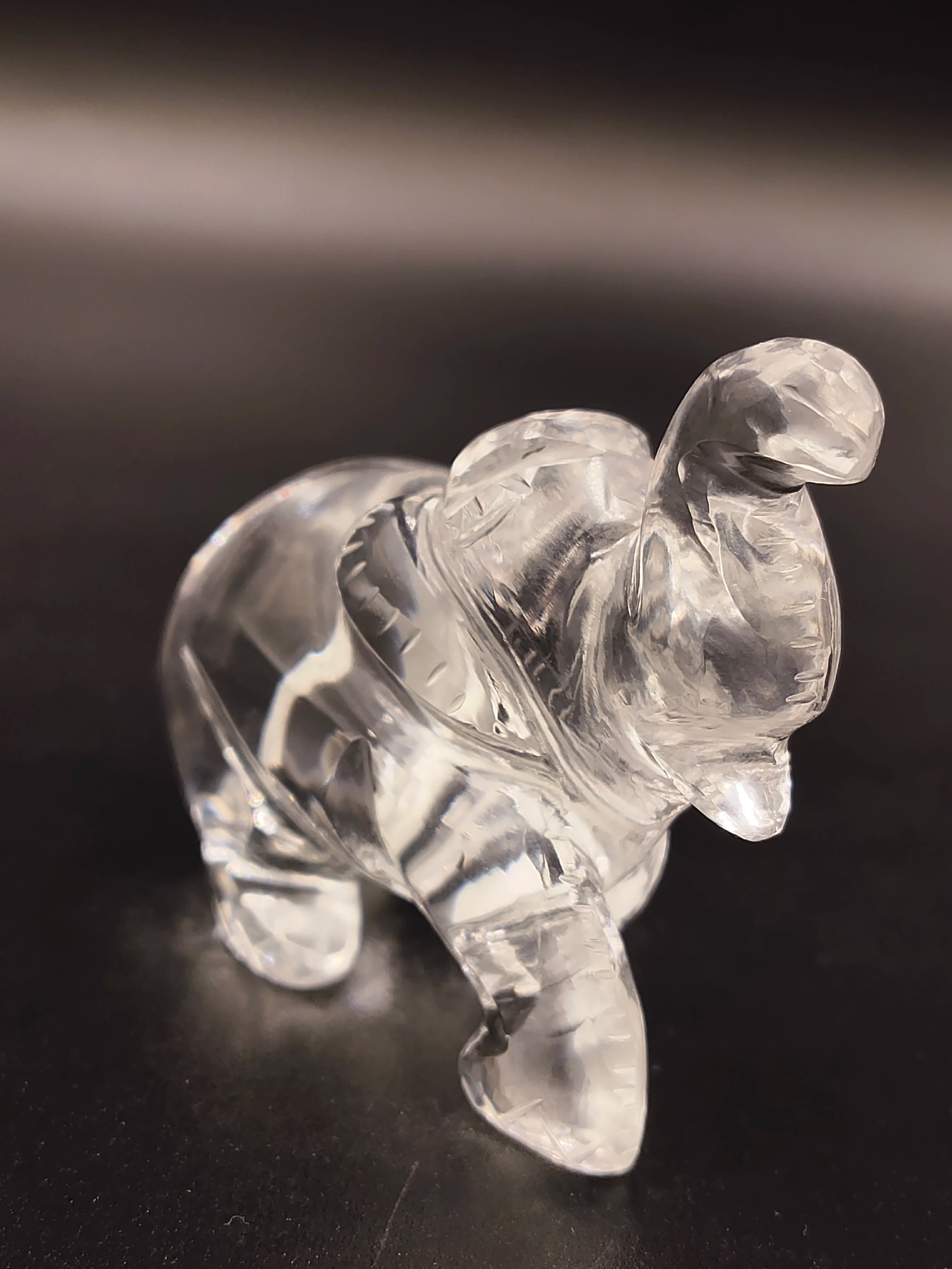 Clear crystal elephant figurine sculpture on a dark surface