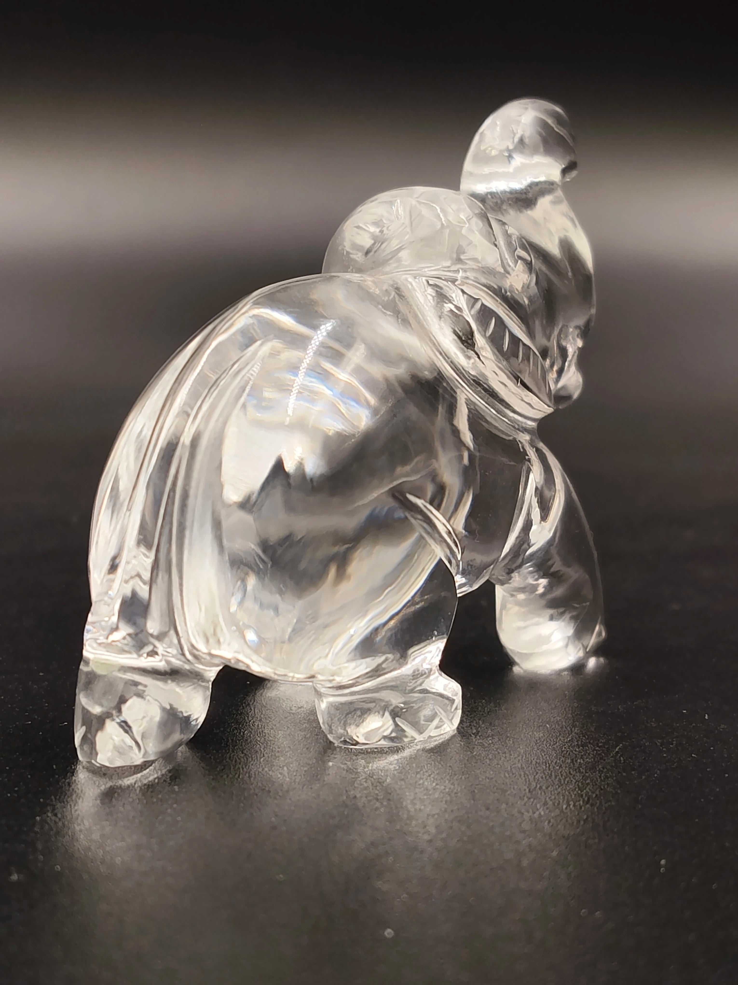 Clear crystal elephant figurine sculpture on dark surface, side view