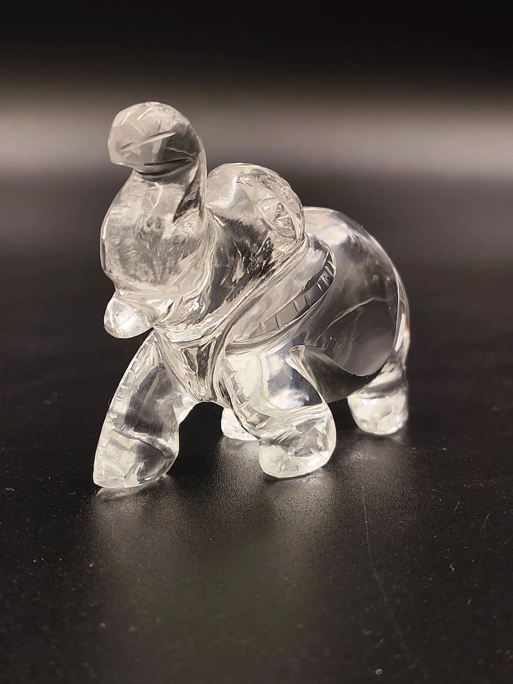 Clear crystal miniature elephant sculpture with detailed carving on black surface