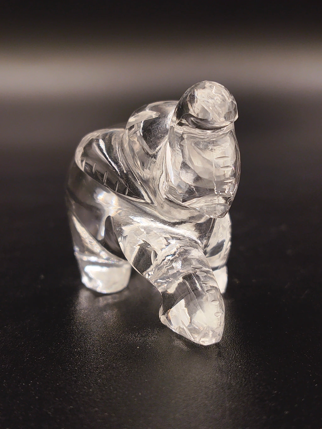 Clear crystal elephant figurine sculpture facing forward on black surface