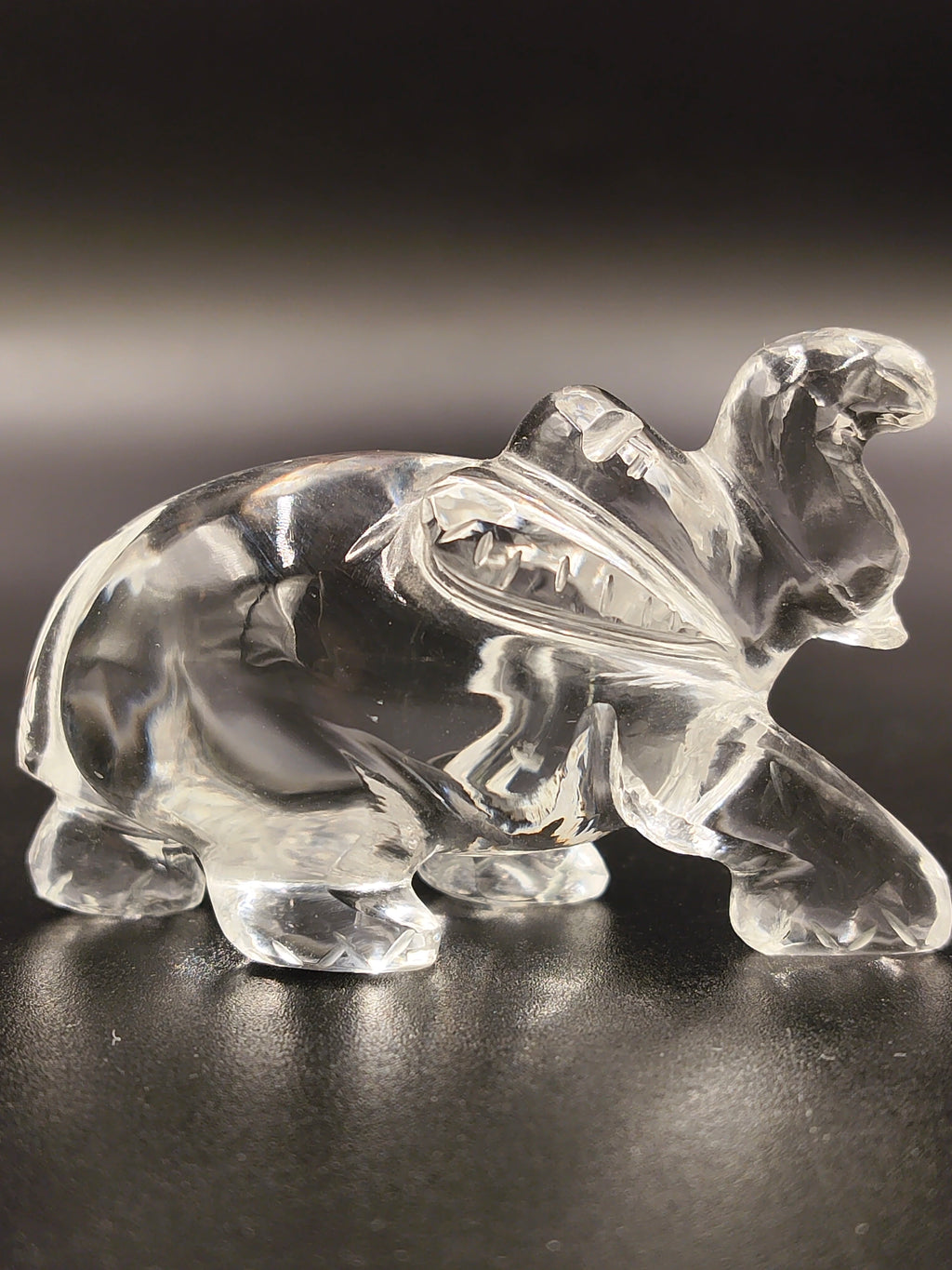 Small clear crystal elephant figurine sculpture on black surface