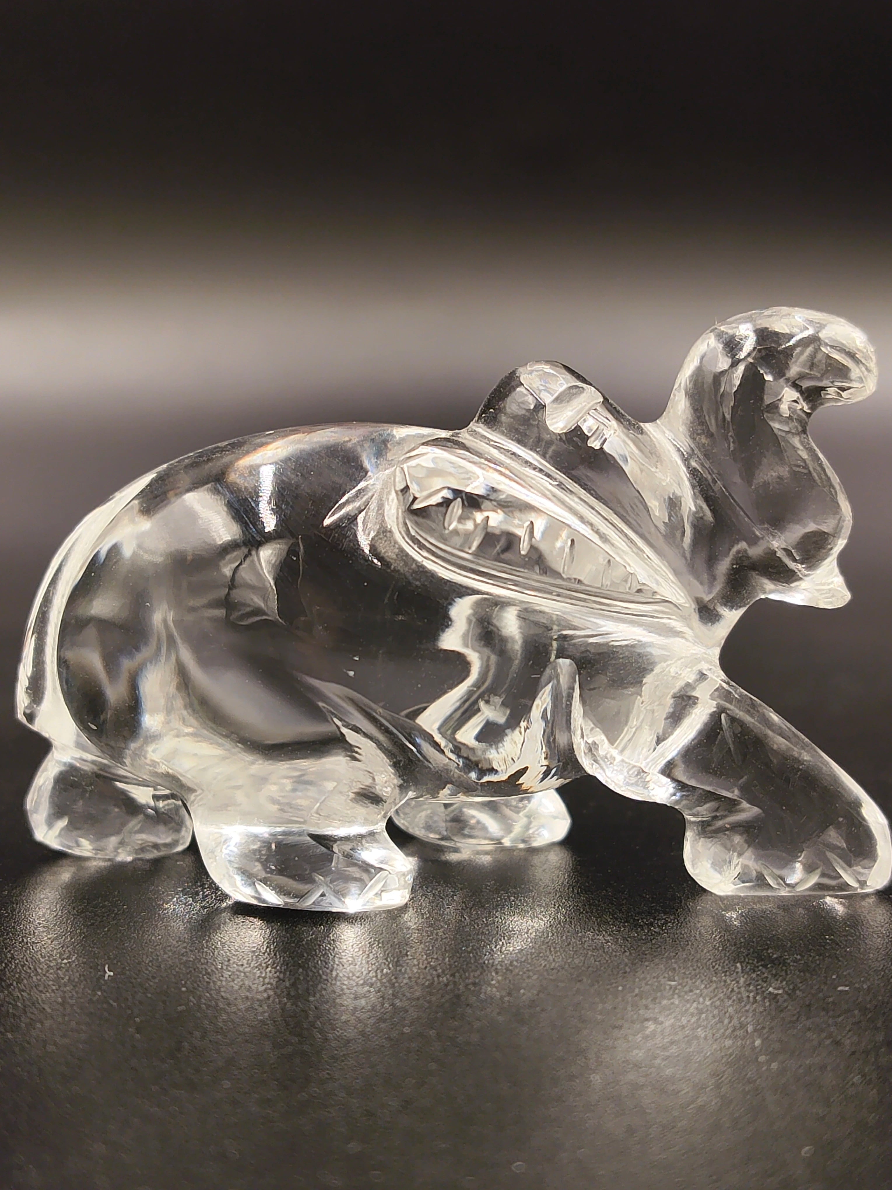 Small clear crystal elephant figurine sculpture on black surface