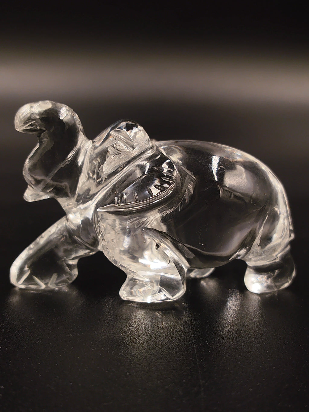 Clear crystal elephant figurine sculpture with raised trunk on black surface