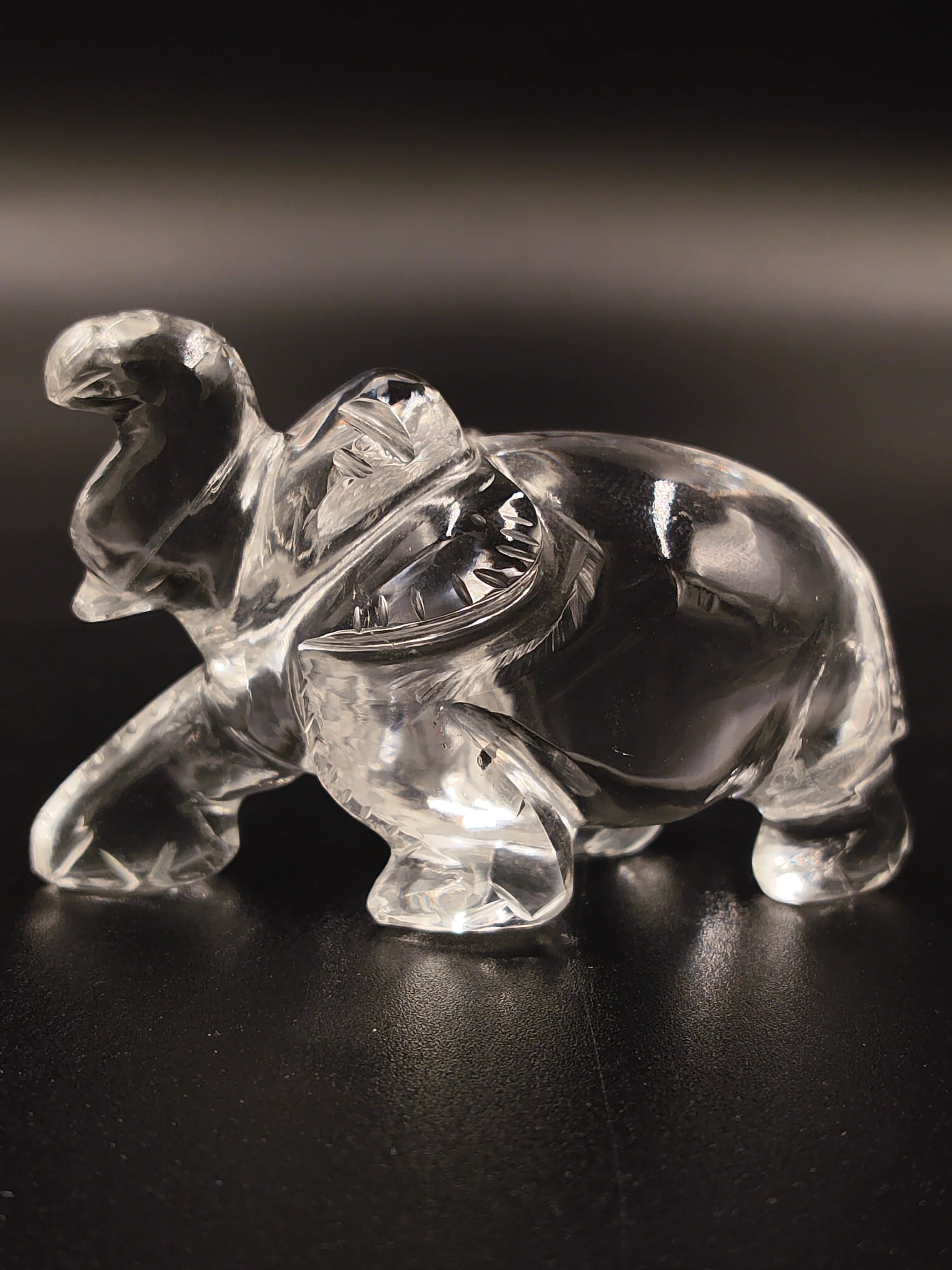 Clear crystal elephant figurine sculpture with raised trunk on black surface