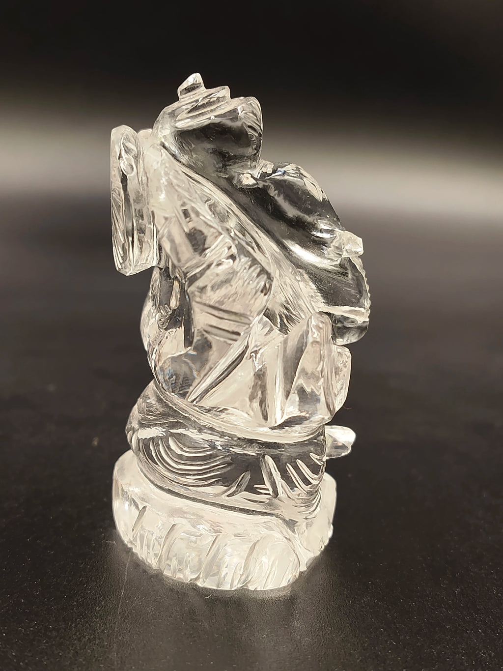 2-inch transparent crystal Ganesh sculpture with intricate detailing on black surface