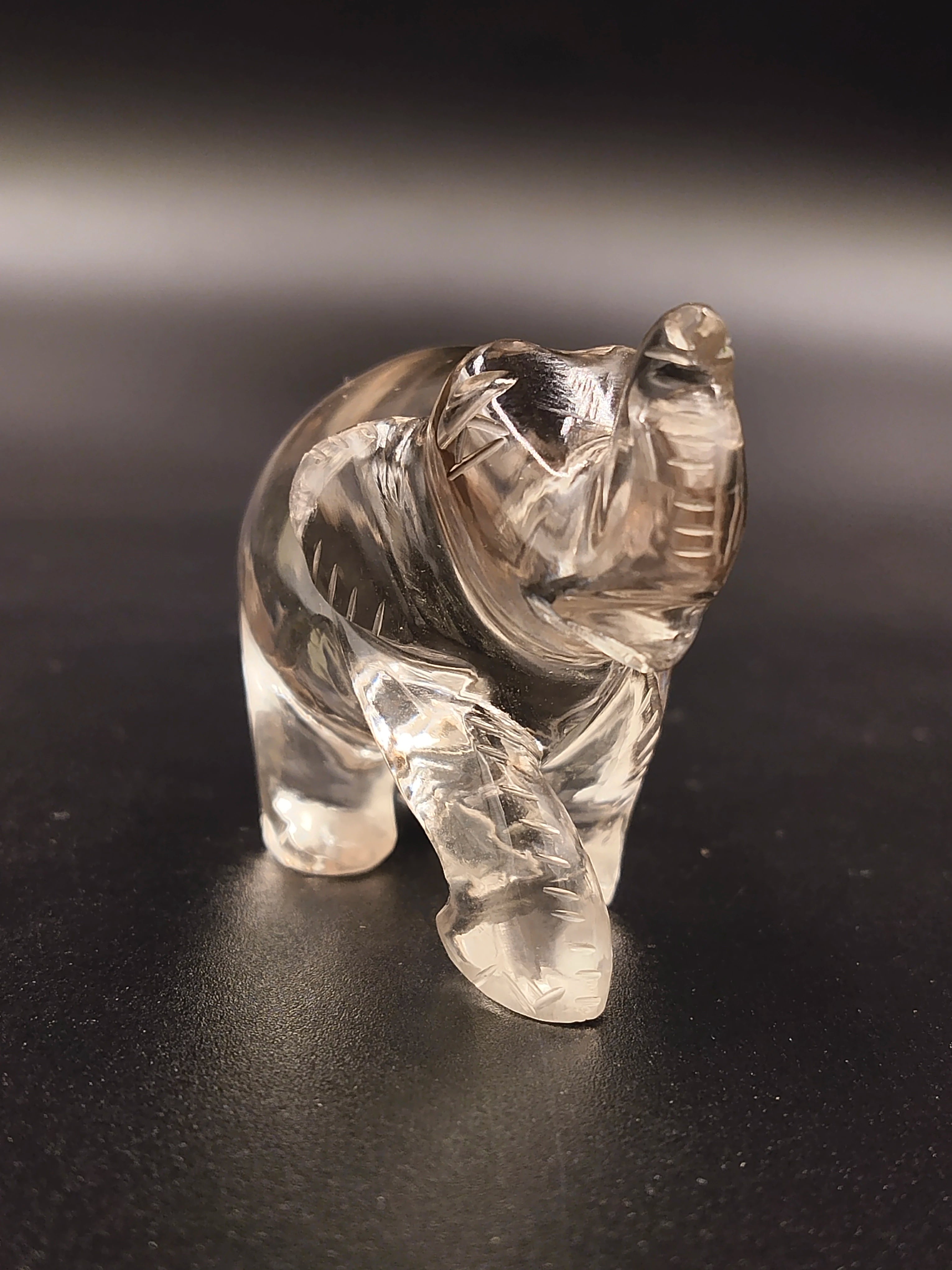 Small clear crystal elephant figurine sculpture on dark surface