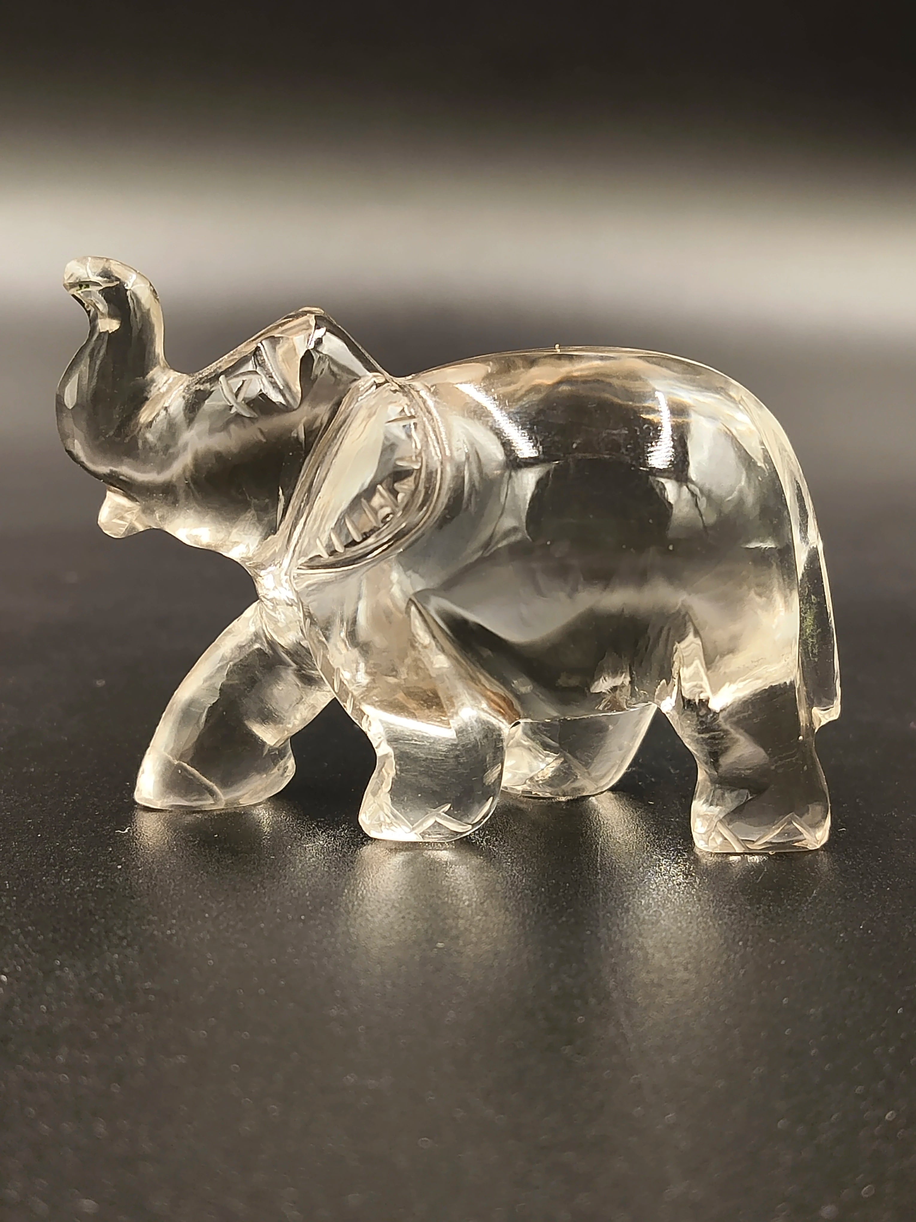 Clear crystal elephant figurine sculpture on black surface side view