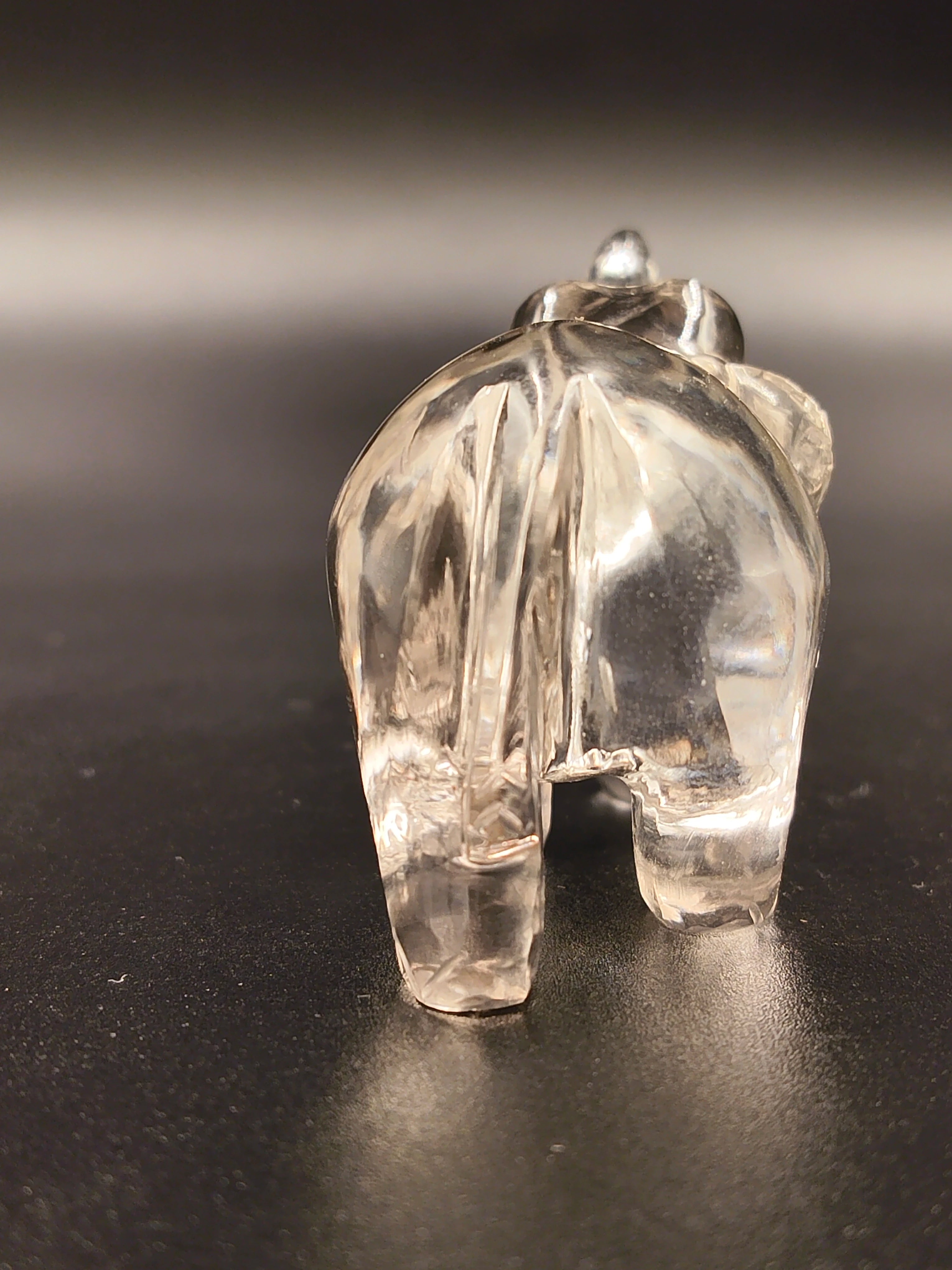 Clear crystal elephant figurine viewed from the back on dark surface