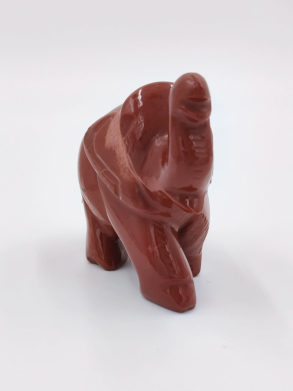 Miniature jasper elephant sculpture with raised trunk in side view
