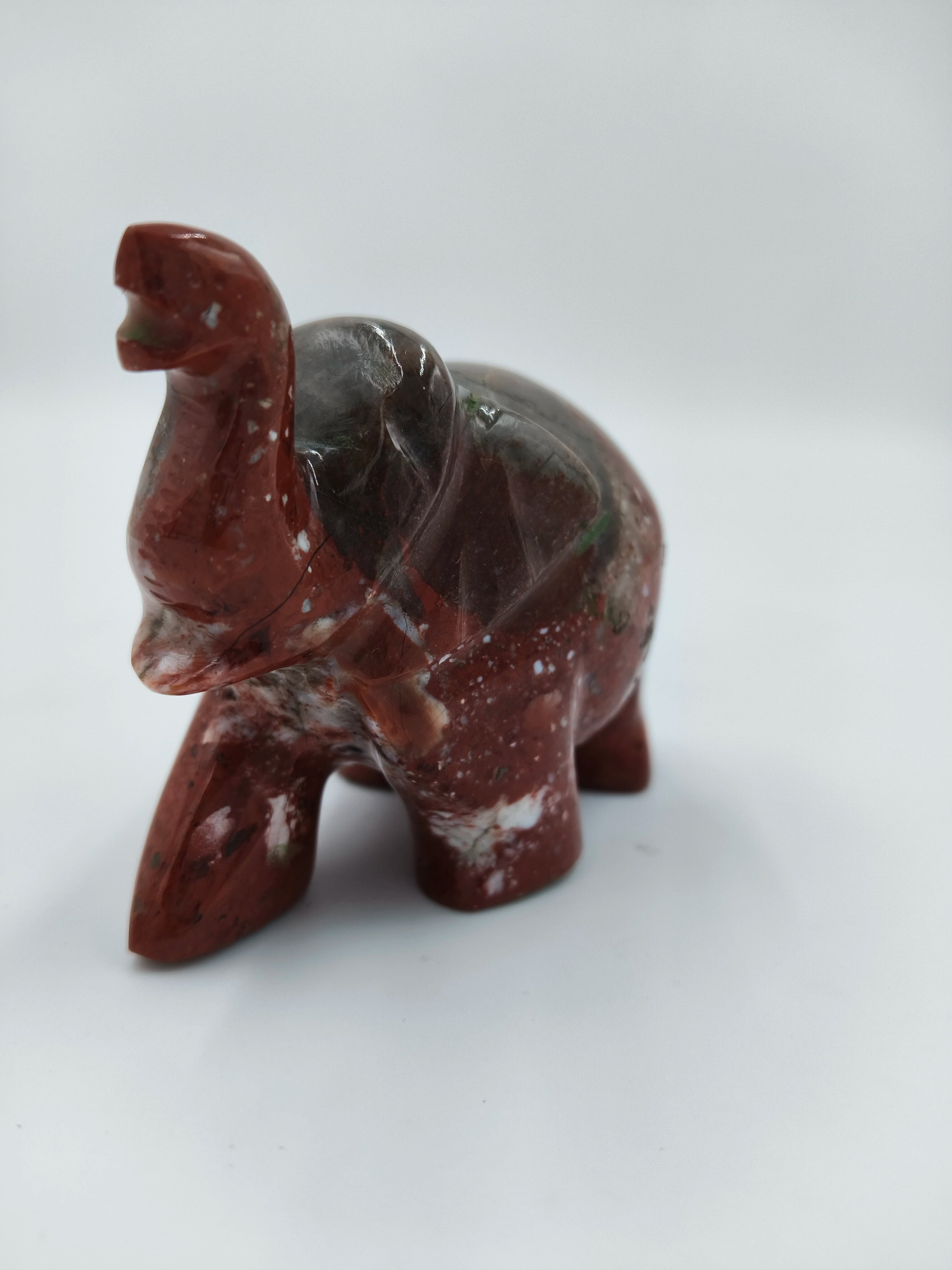 Small polished jasper elephant sculpture with raised trunk, front side view