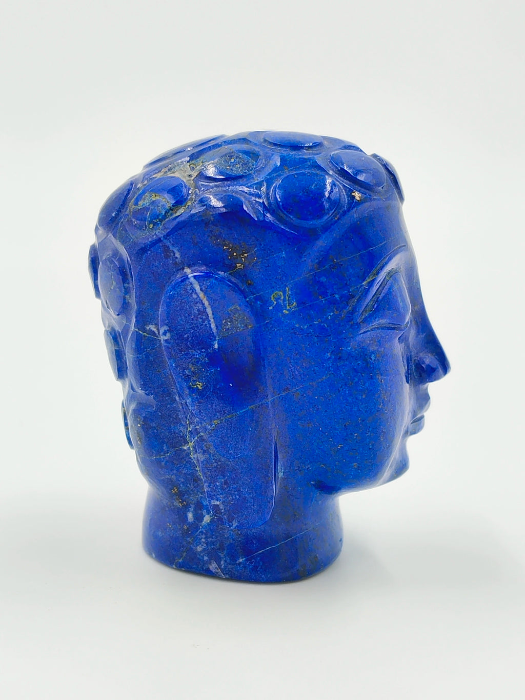 Side view of a small carved blue lapis lazuli Buddha head sculpture