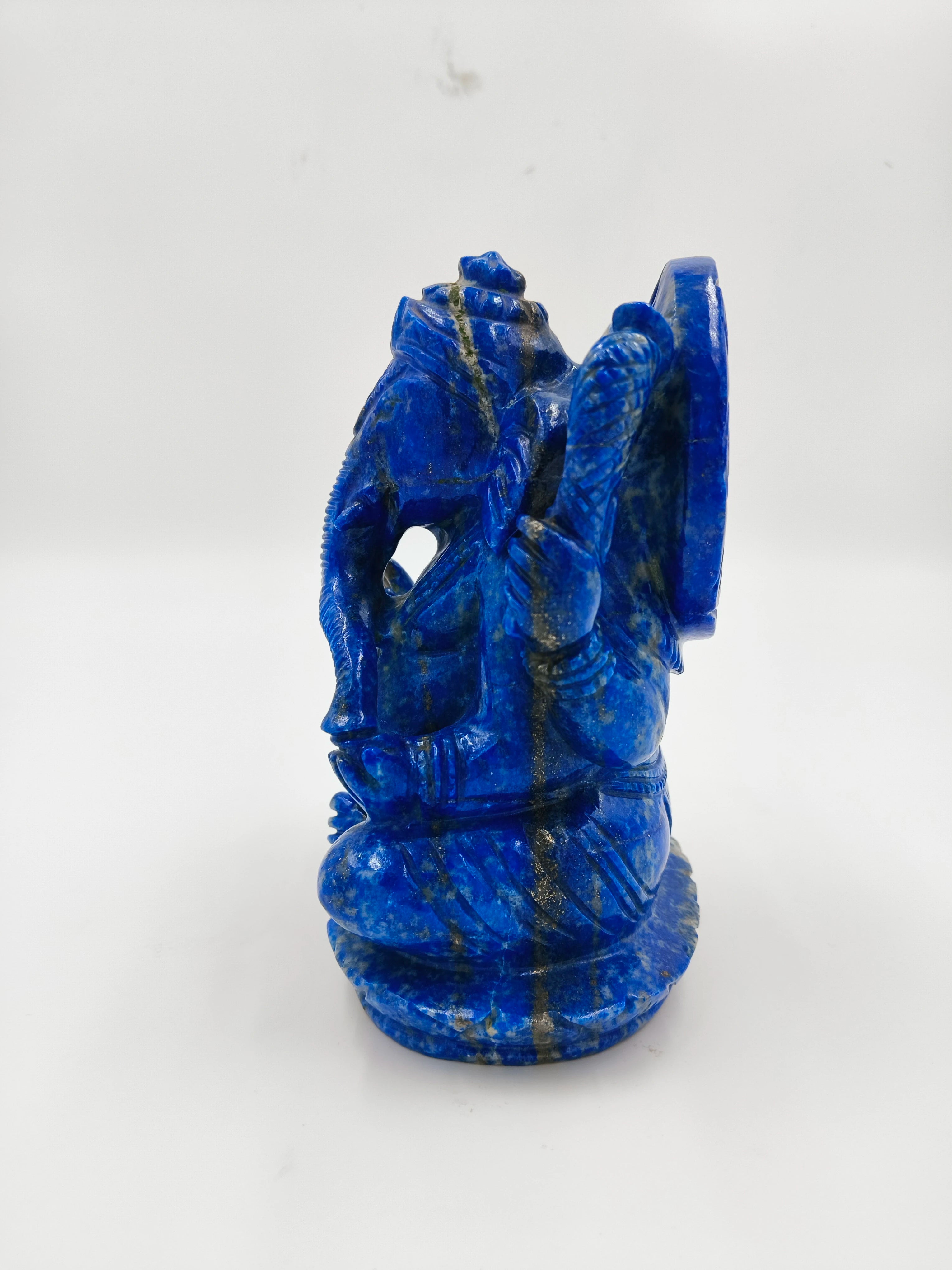 Side view of a blue lapis Ganesh statue sitting on a round base