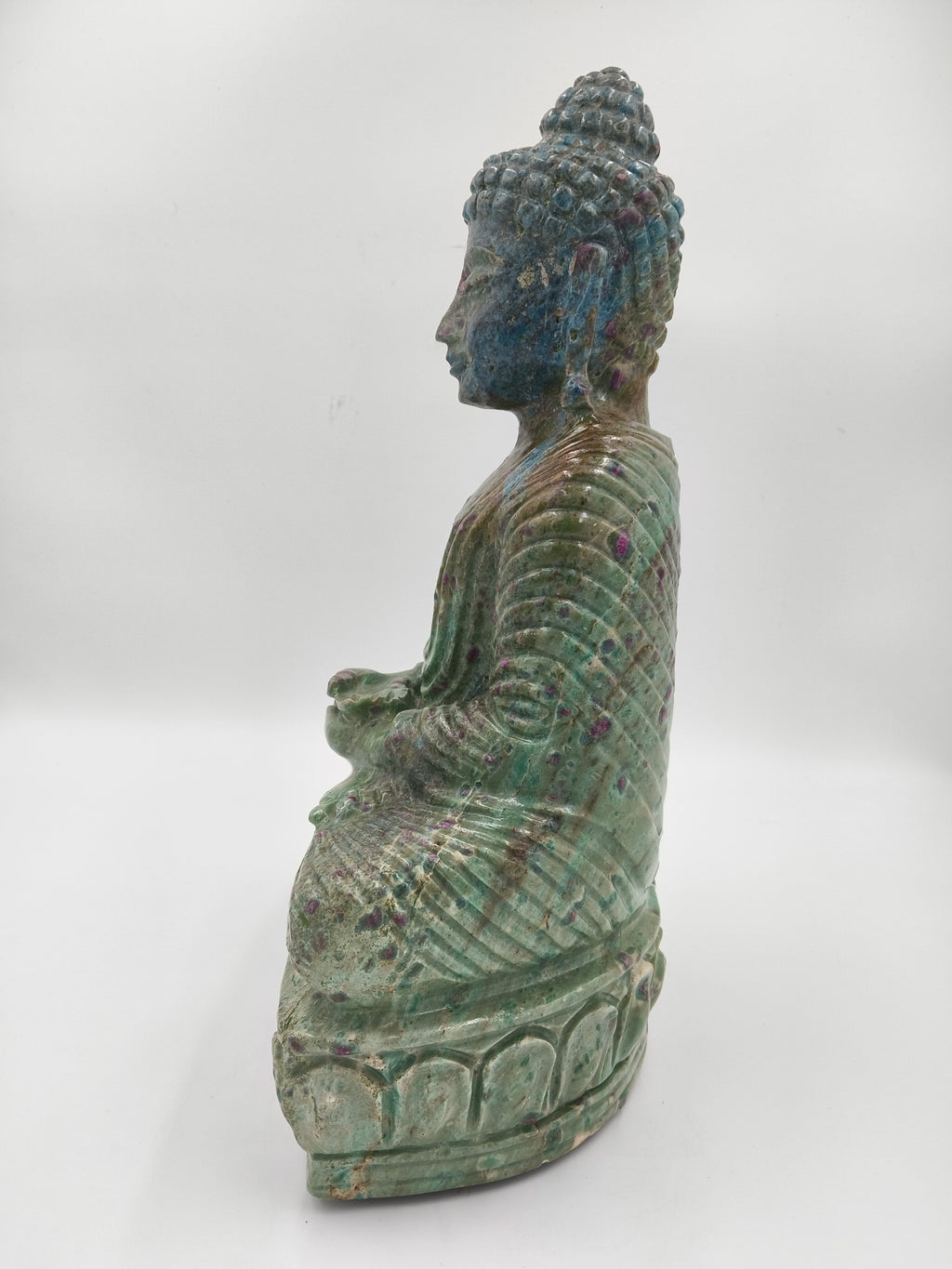Side view of large Rubylite Buddha sculpture with green and purple hues