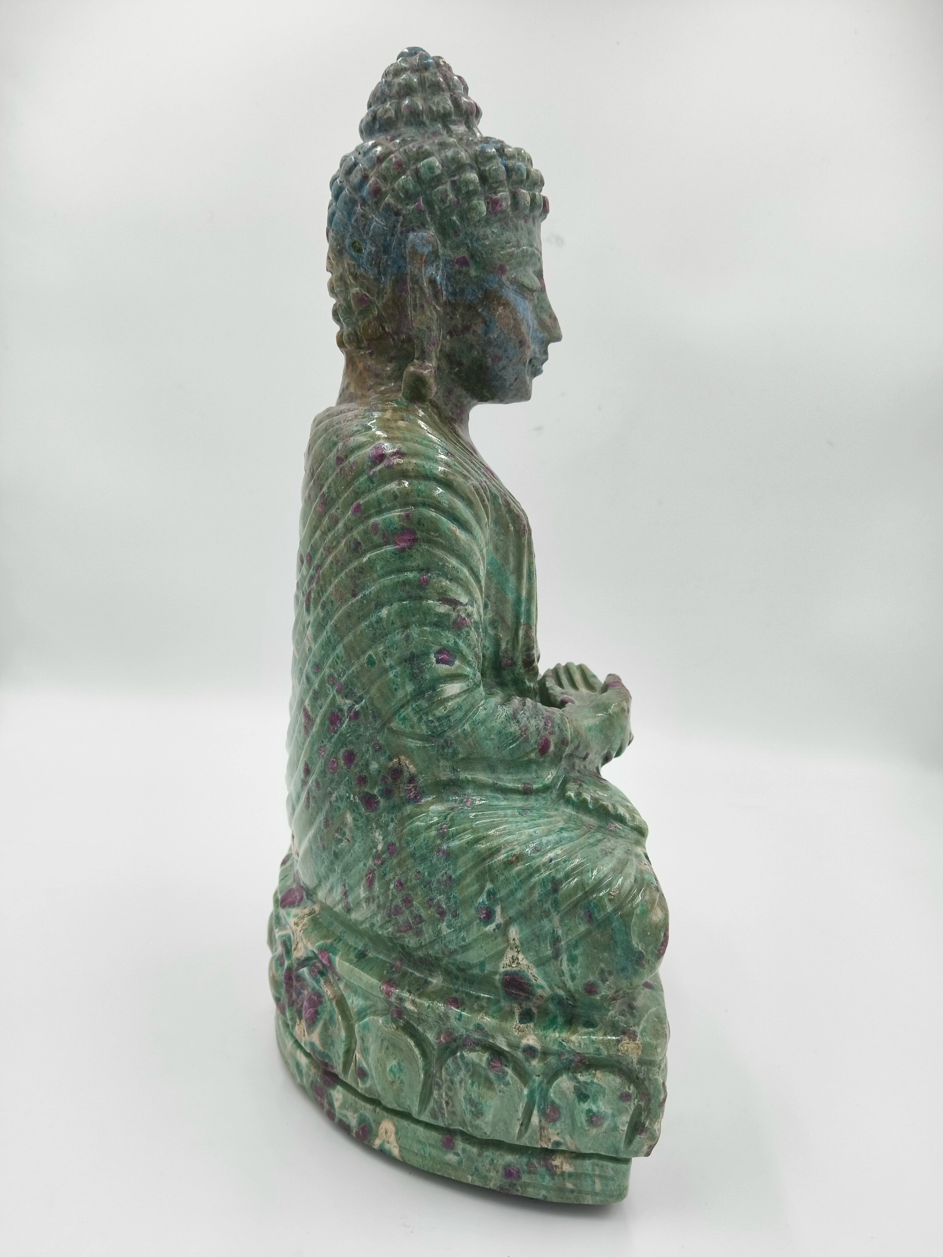 Side view of a green and purple Rubylite Buddha statue sitting in meditation