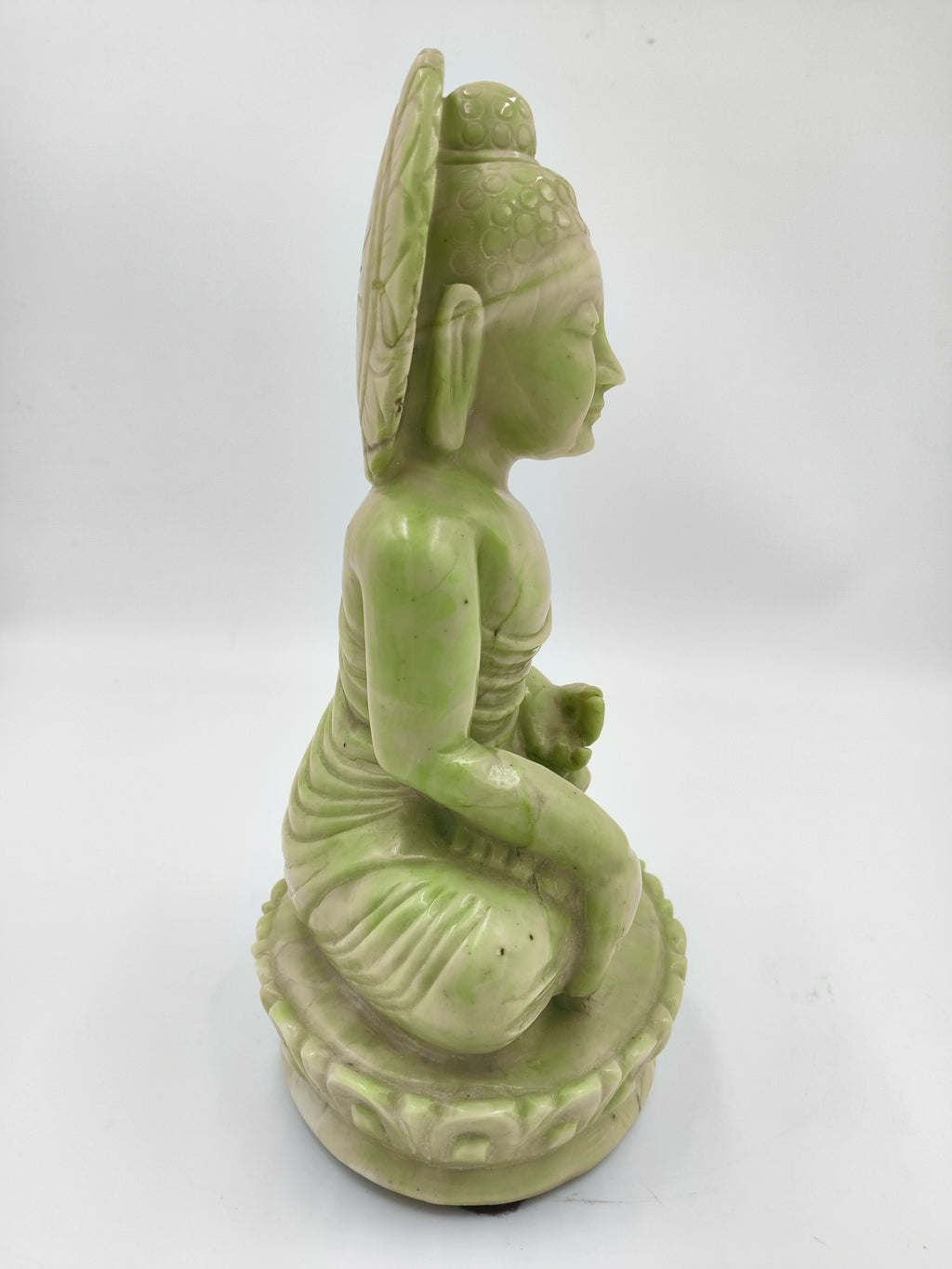 Side view of green serpentine stone Buddha sculpture seated on lotus pedestal