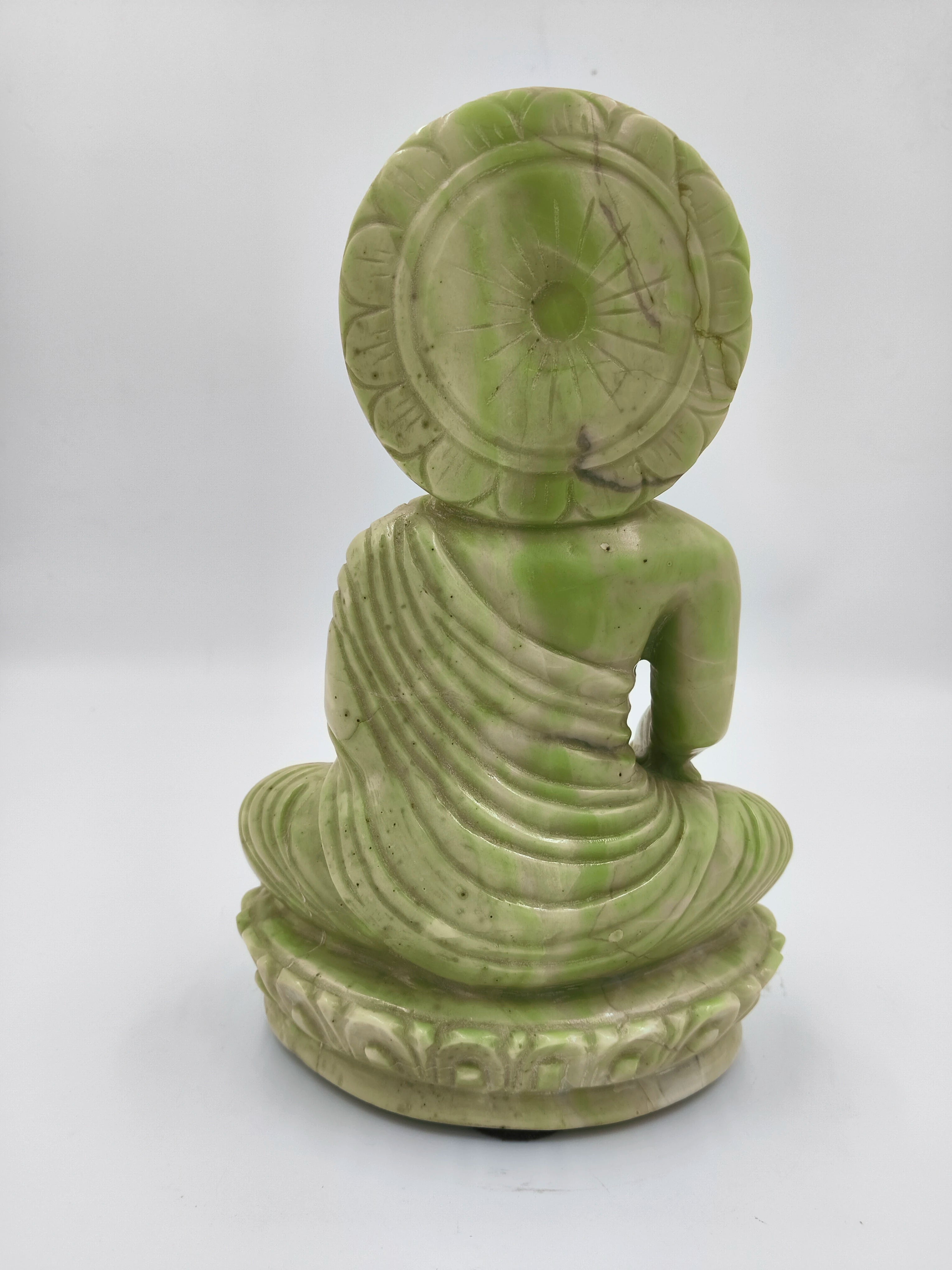 Back view of large serpentine Buddha sculpture sitting on lotus base