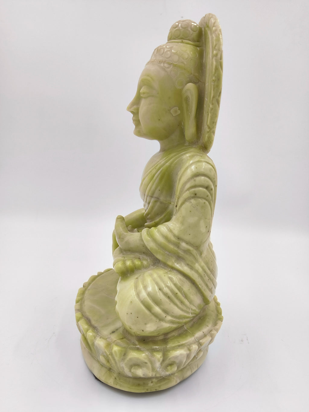 Side view of large serpentine Buddha statue in meditation pose on lotus base
