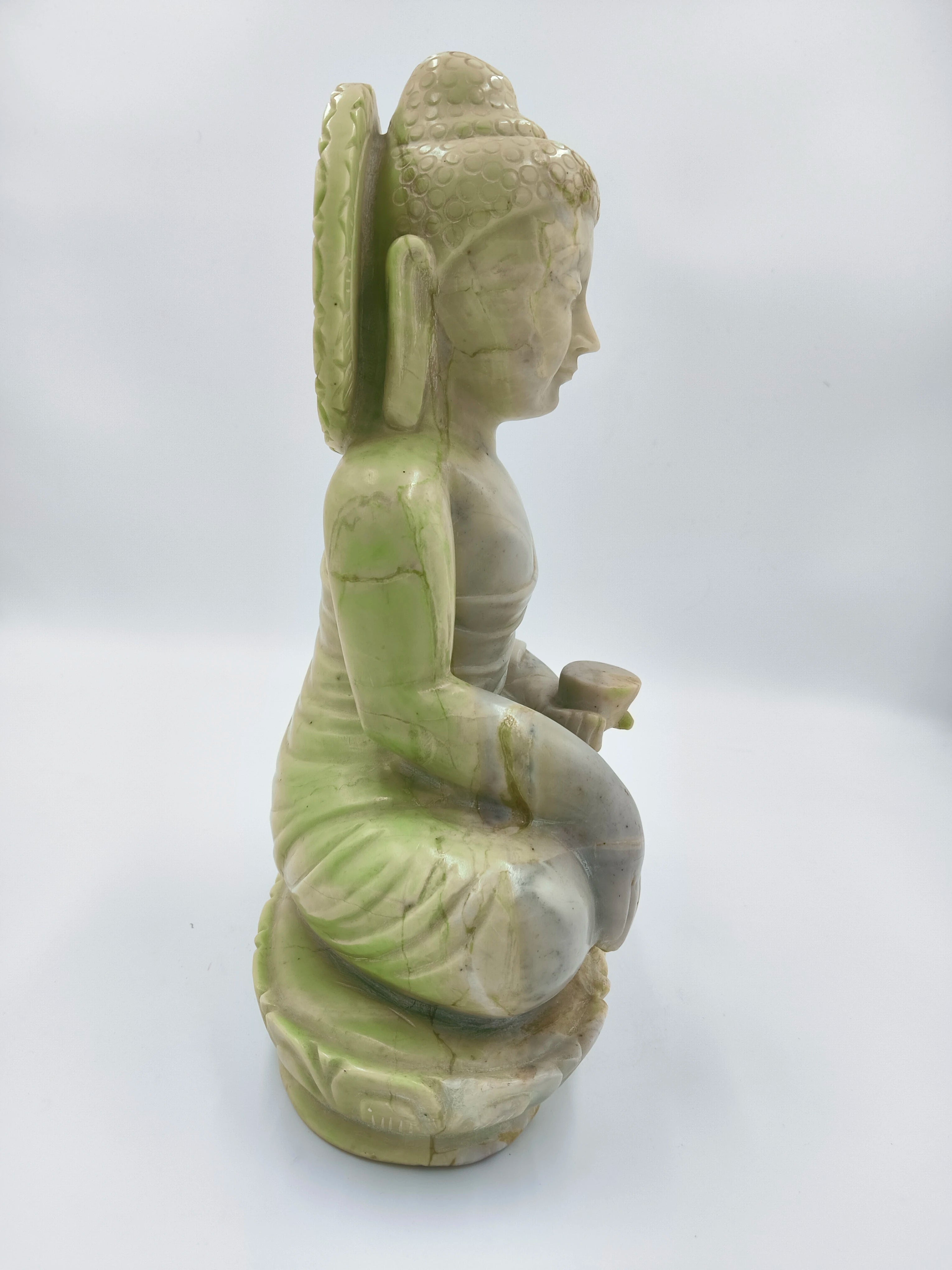 Side view of green and white serpentine stone Buddha sculpture seated in meditation