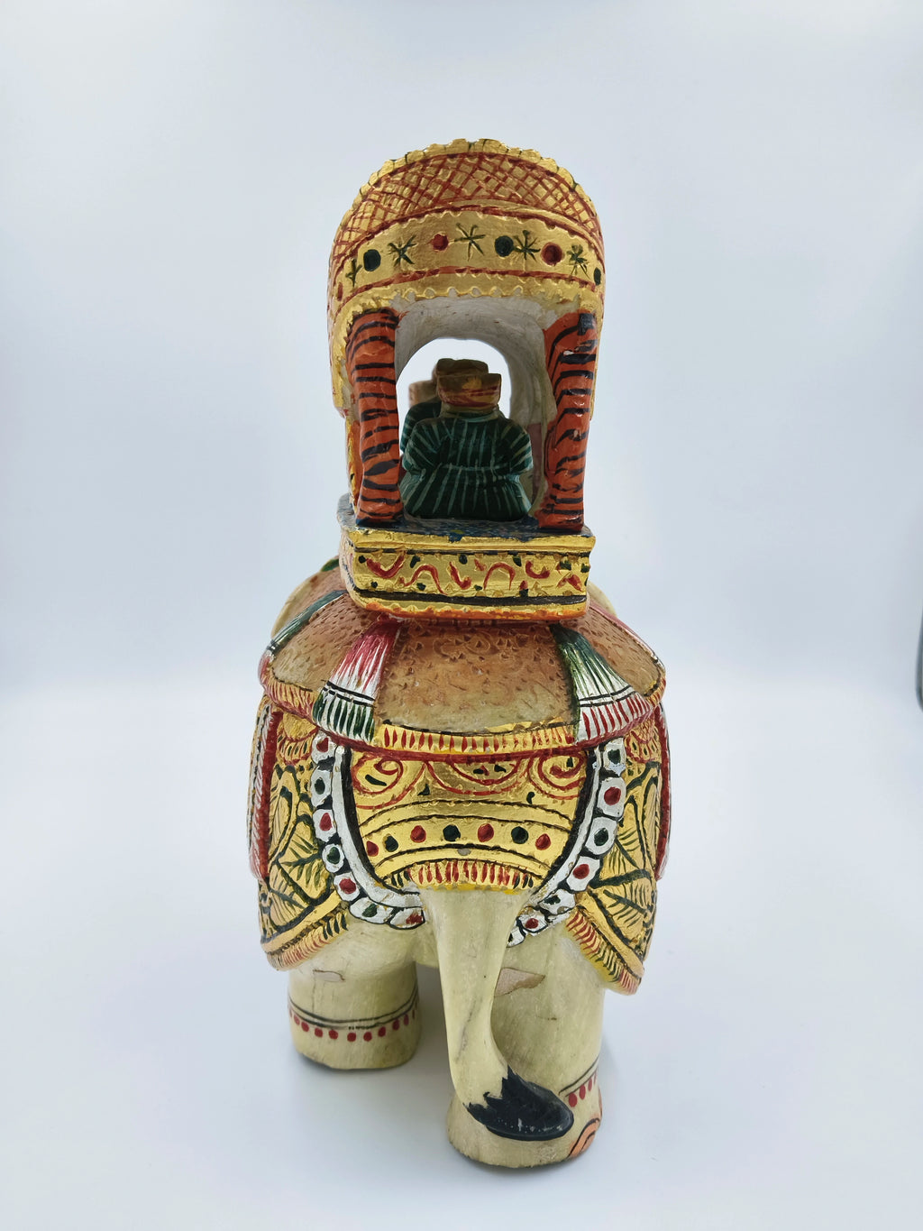 Rear view of a painted serpentine elephant ambari sculpture with a seated figurine