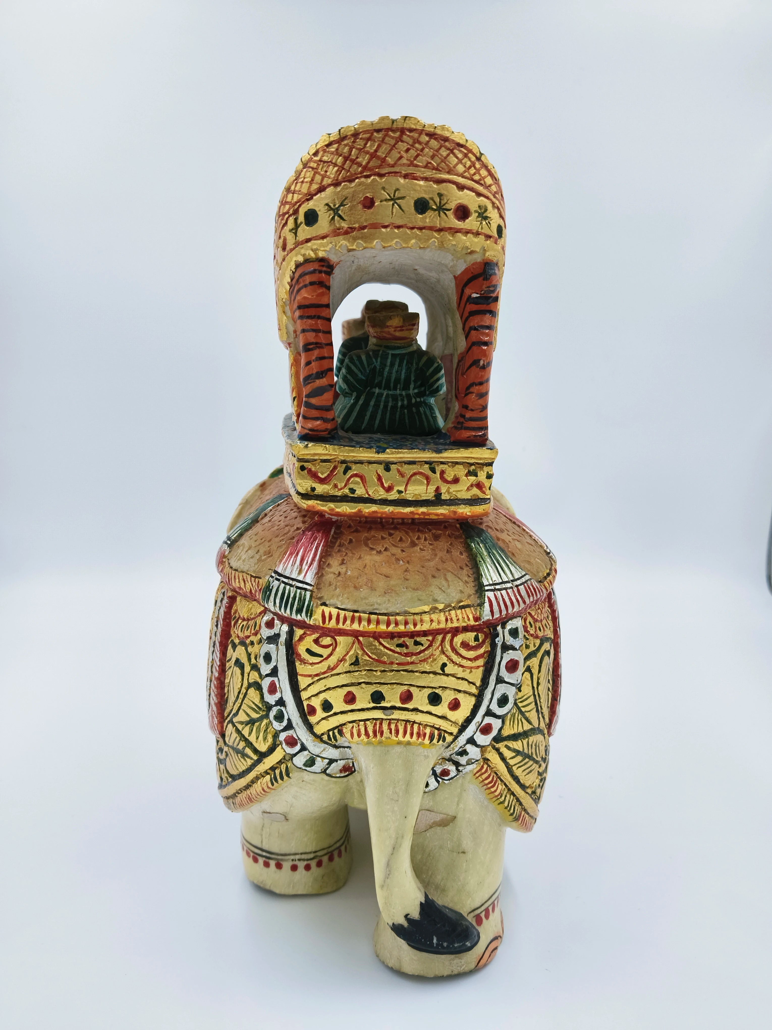 Rear view of a painted serpentine elephant ambari sculpture with a seated figurine