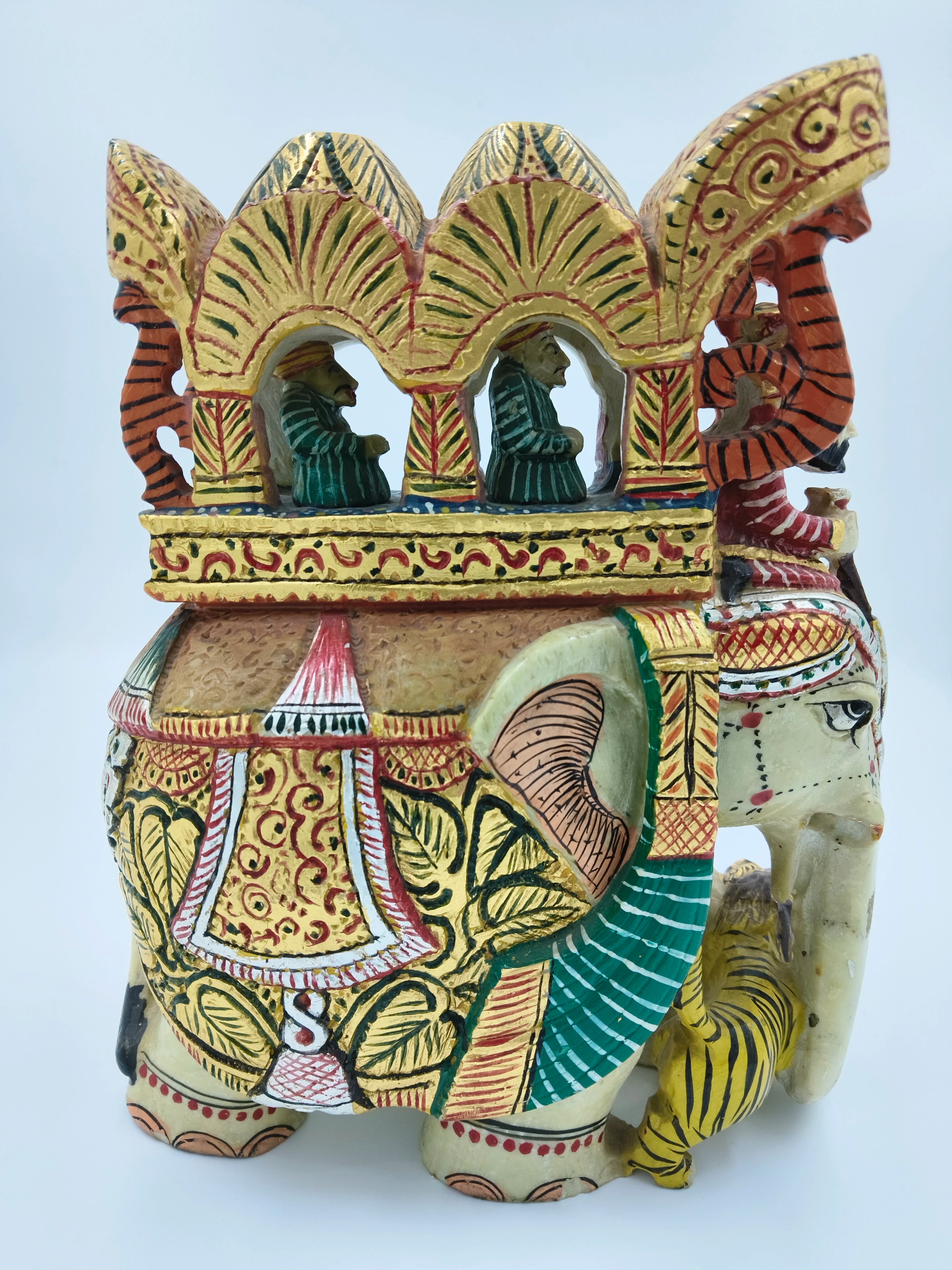 Side view of large serpentine elephant ambari sculpture with colorful painting and three seated figures