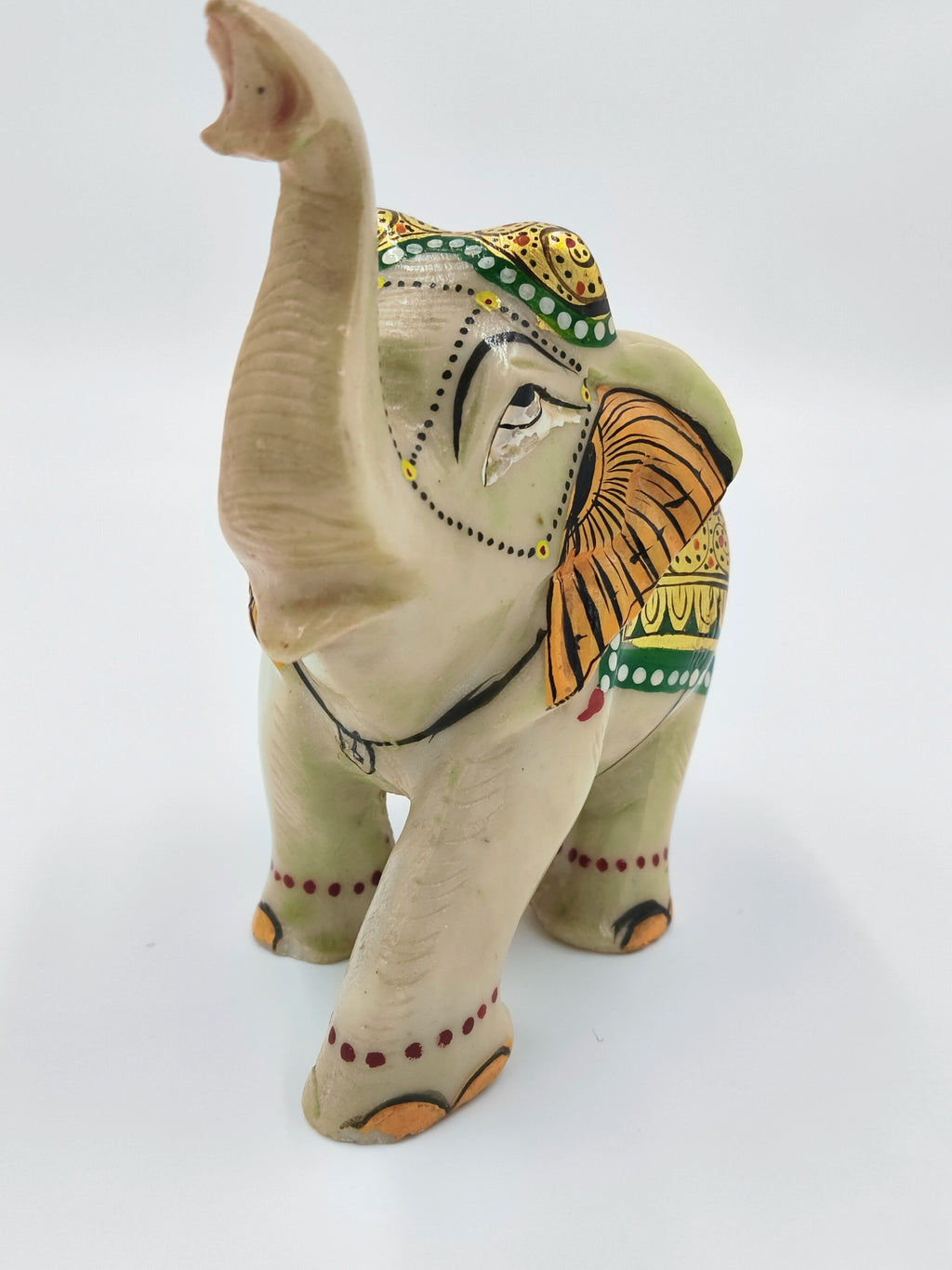 Serpentine elephant sculpture with painted decorative details, front view