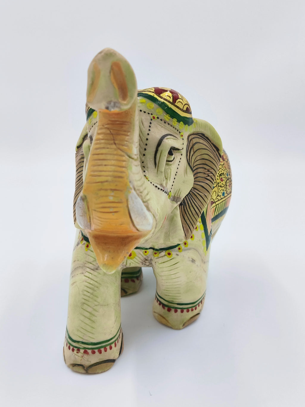 Front view of a hand-painted serpentine elephant sculpture with decorative patterns
