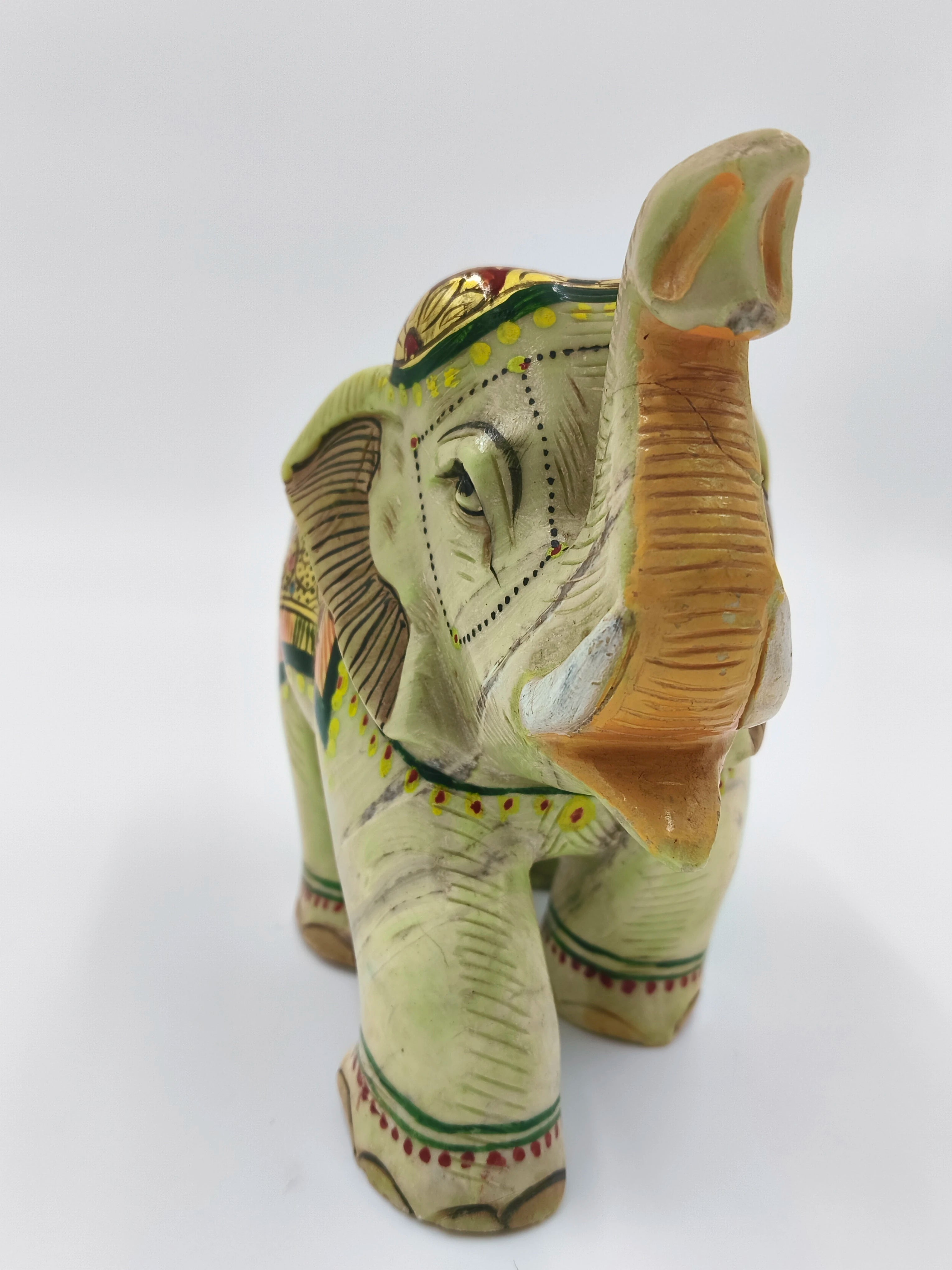 Hand-painted serpentine stone elephant sculpture with raised trunk, front view