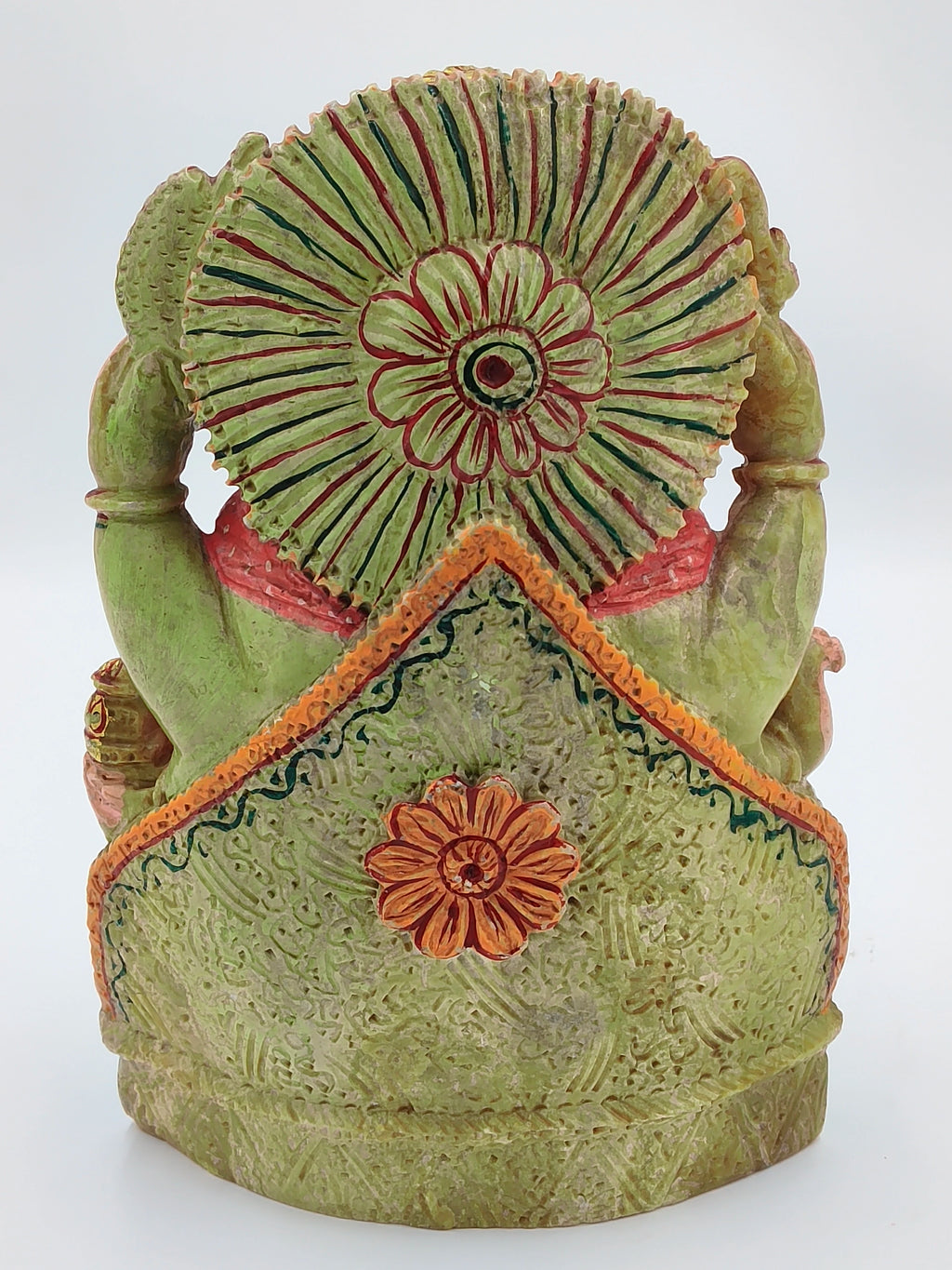 Back view of painted serpentine sculpture of deity Ganesh with floral decorations