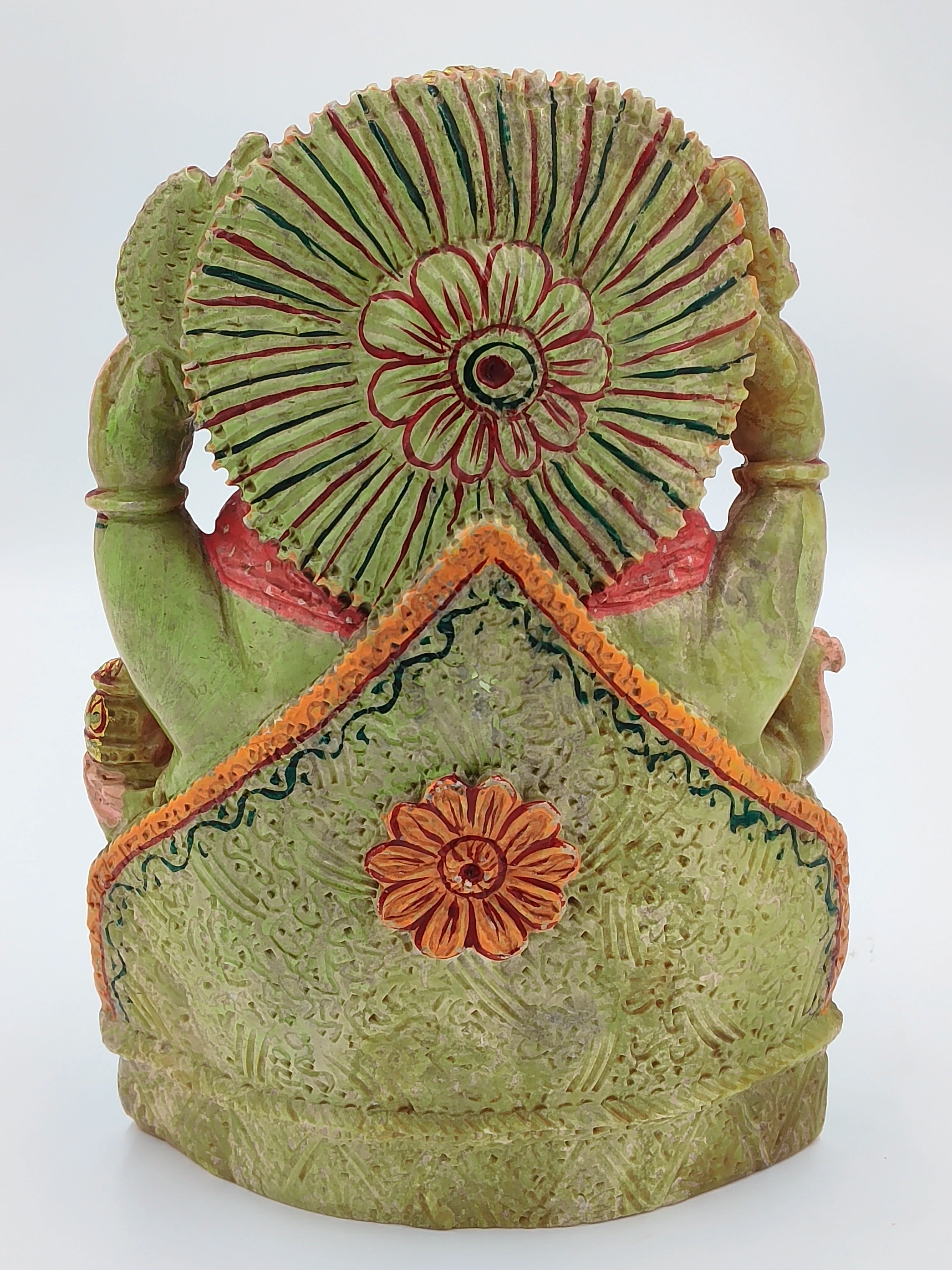 Back view of painted serpentine sculpture of deity Ganesh with floral decorations