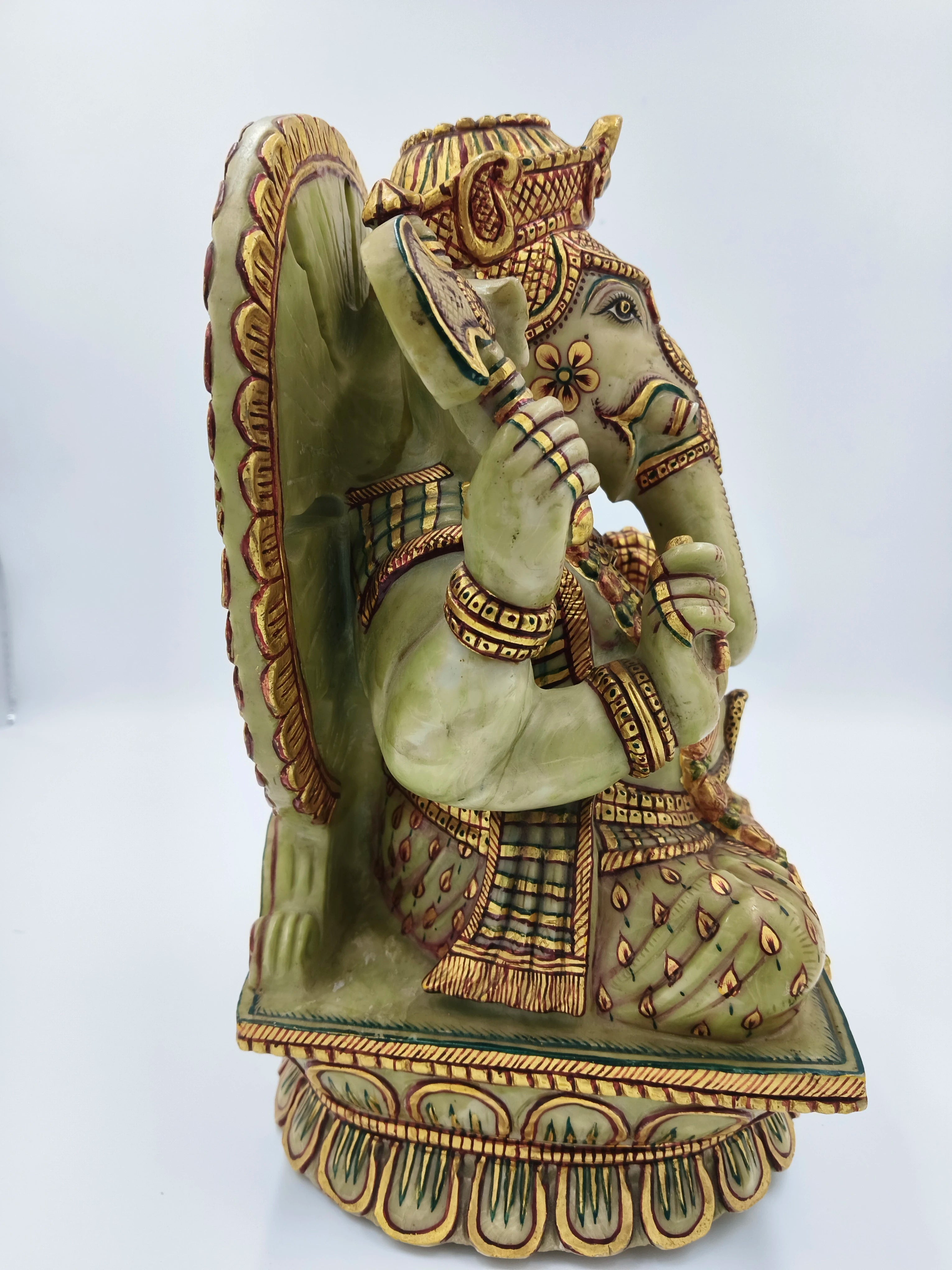 Side view of painted serpentine Ganesh sculpture with intricate gold and green detailing