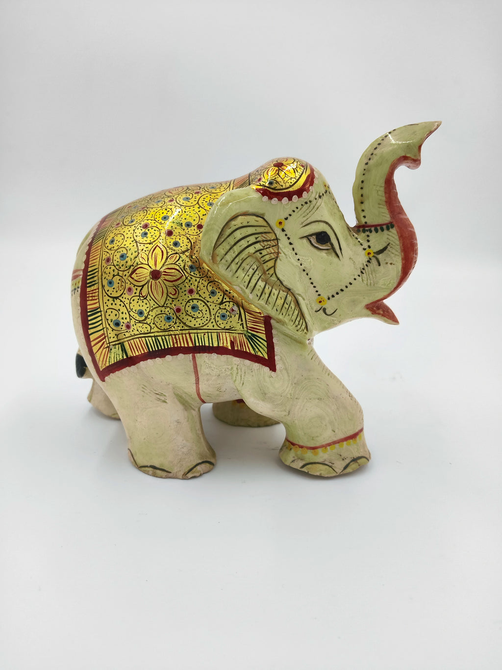 side view of a serpentine elephant figurine with golden and red decorative patterns