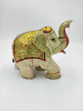 side view of a serpentine elephant figurine with golden and red decorative patterns