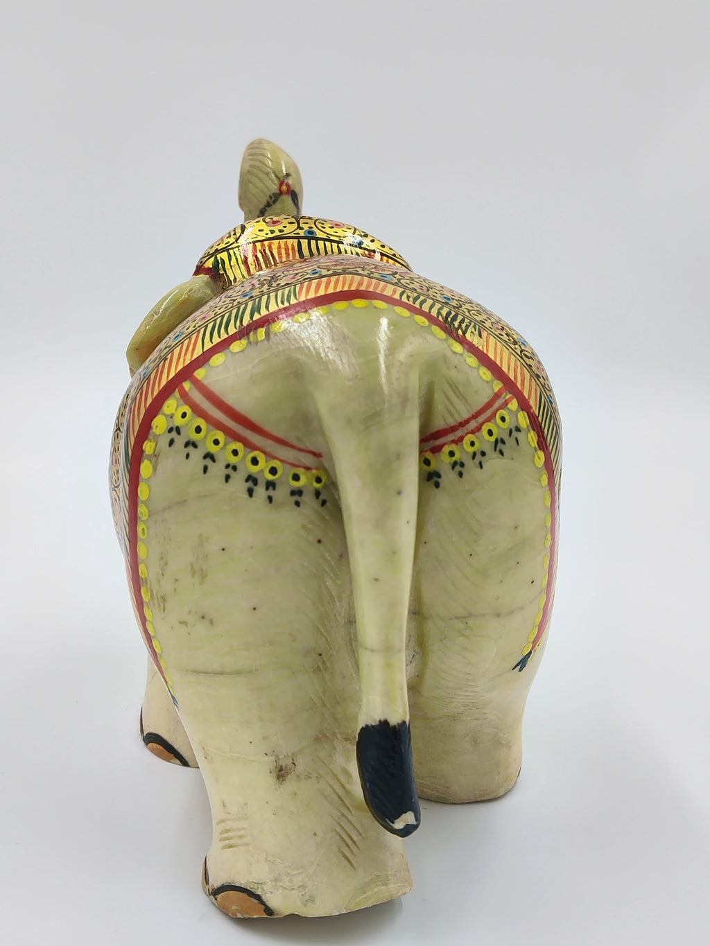 Rear view of a painted serpentine stone elephant sculpture with decorative patterns