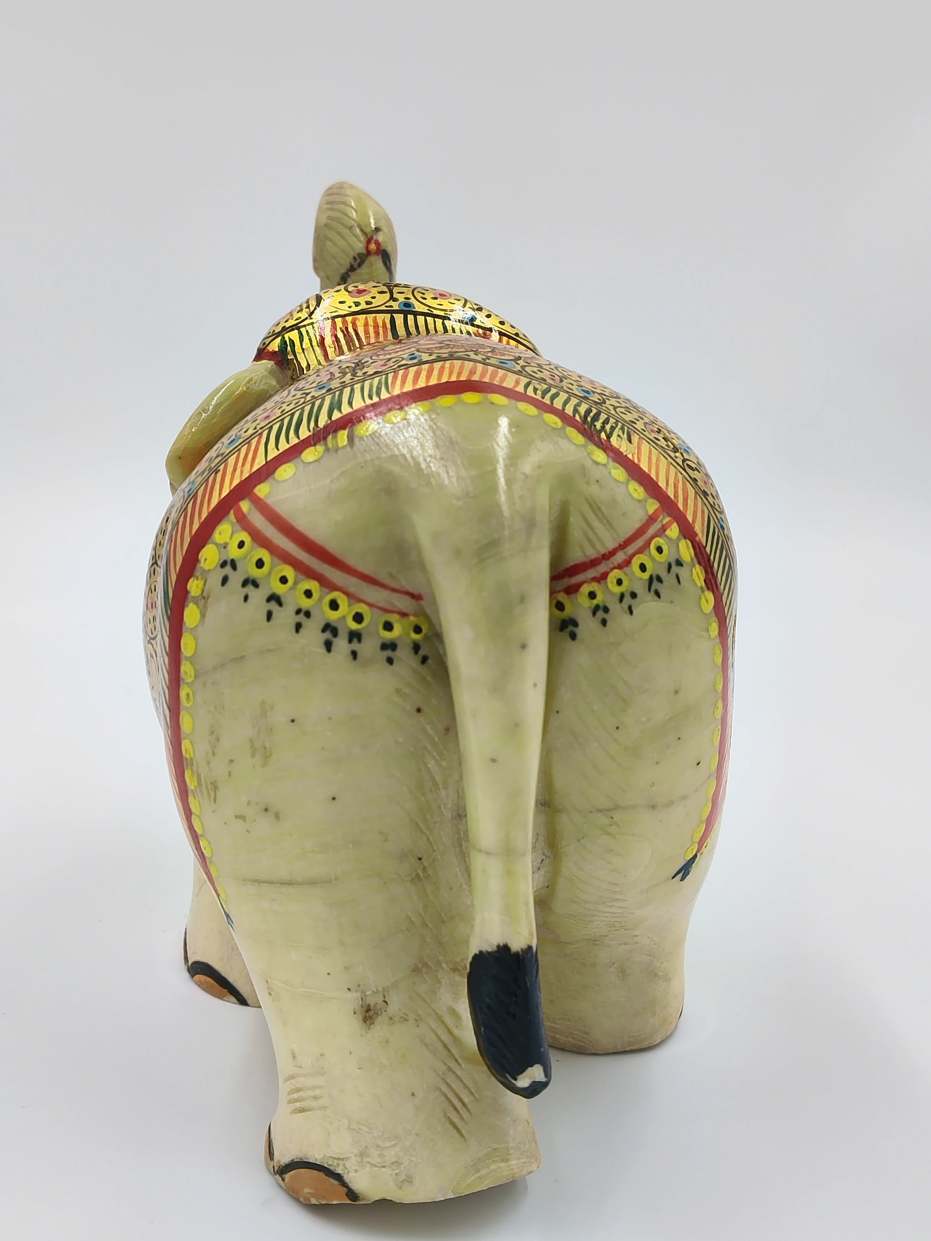 Rear view of a painted serpentine stone elephant sculpture with decorative patterns
