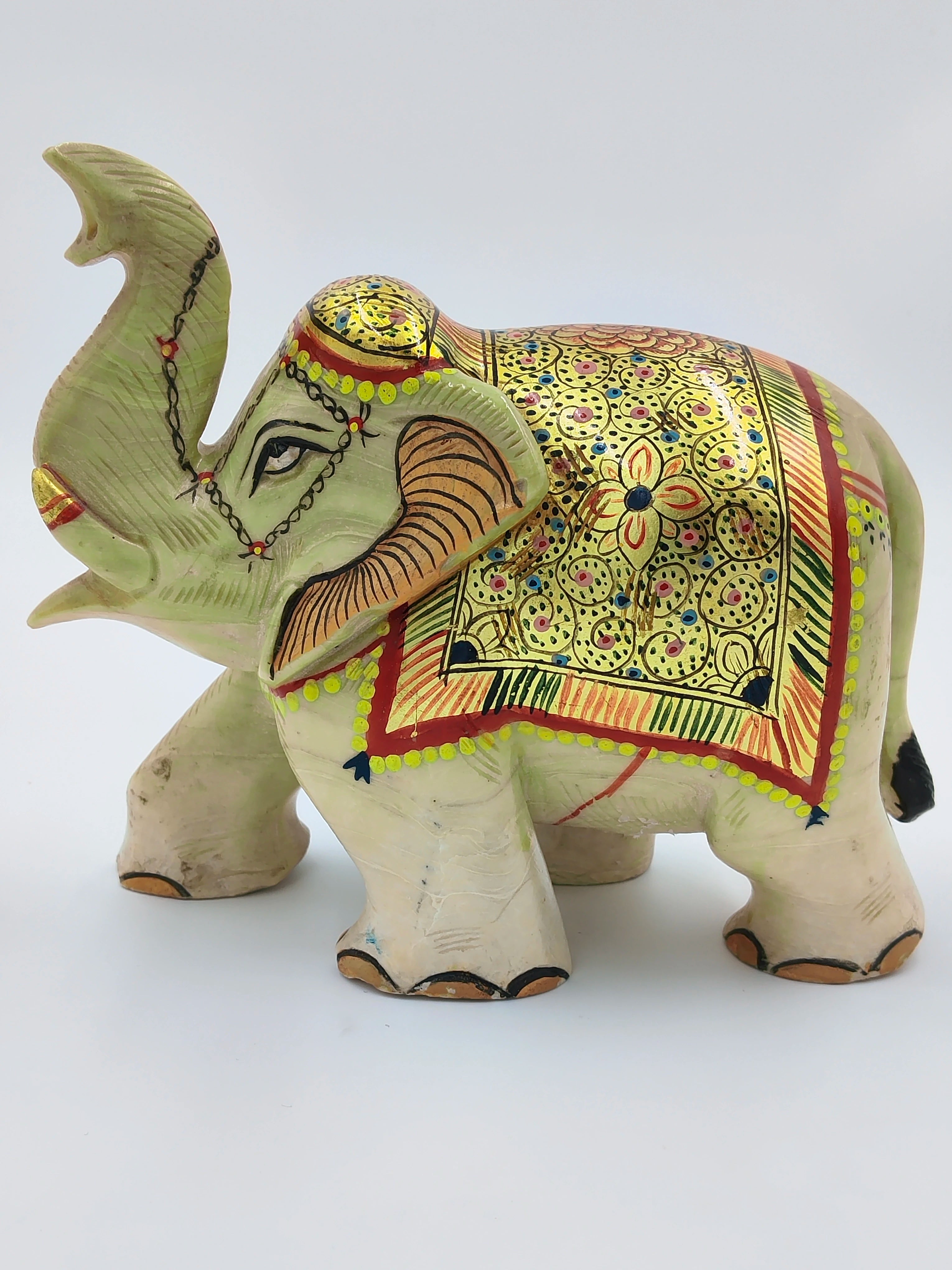 Serpentine elephant sculpture with decorative gold and colorful patterns side view