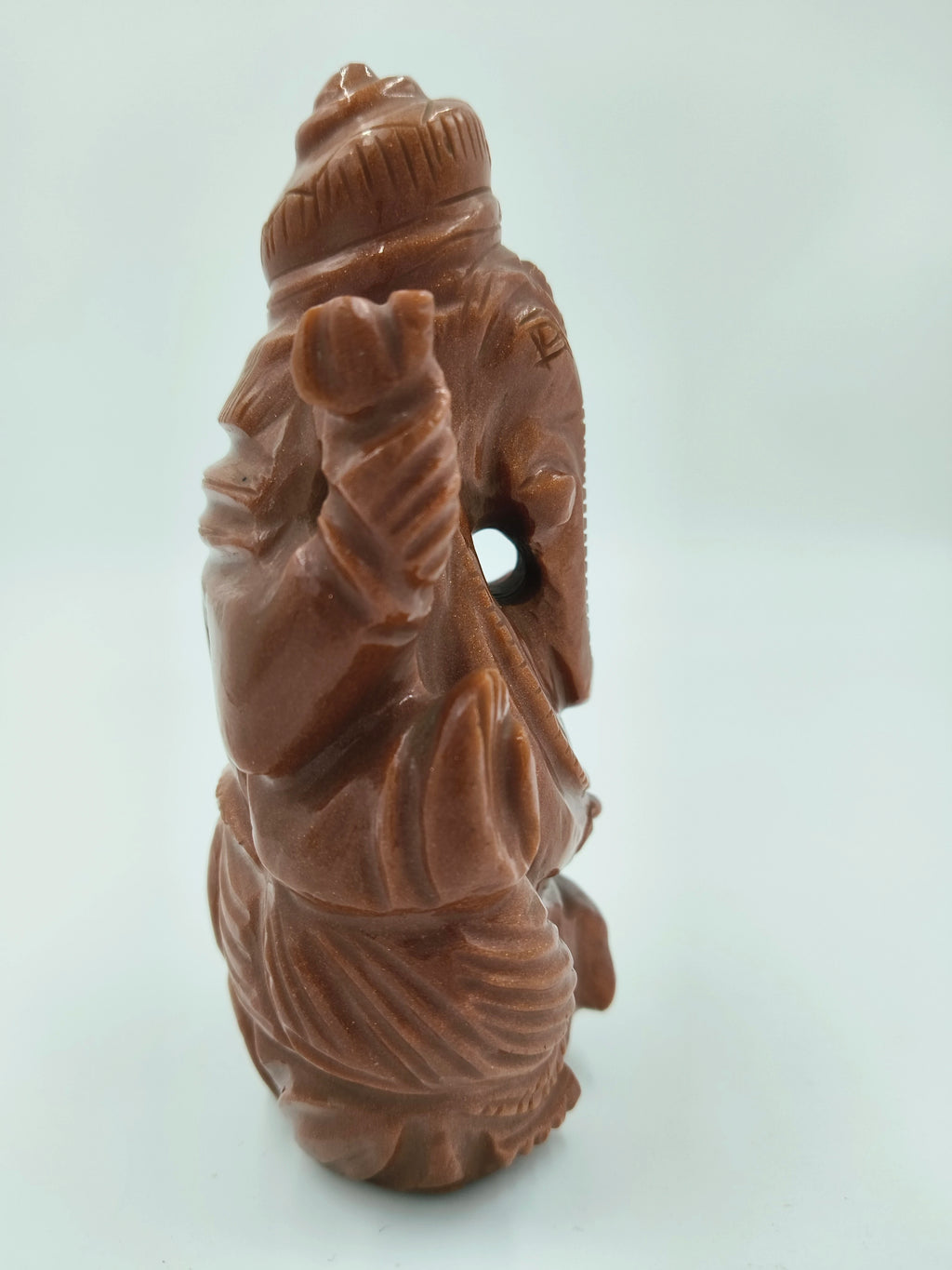 Side view of medium sunstone Ganesh statue with detailed carving